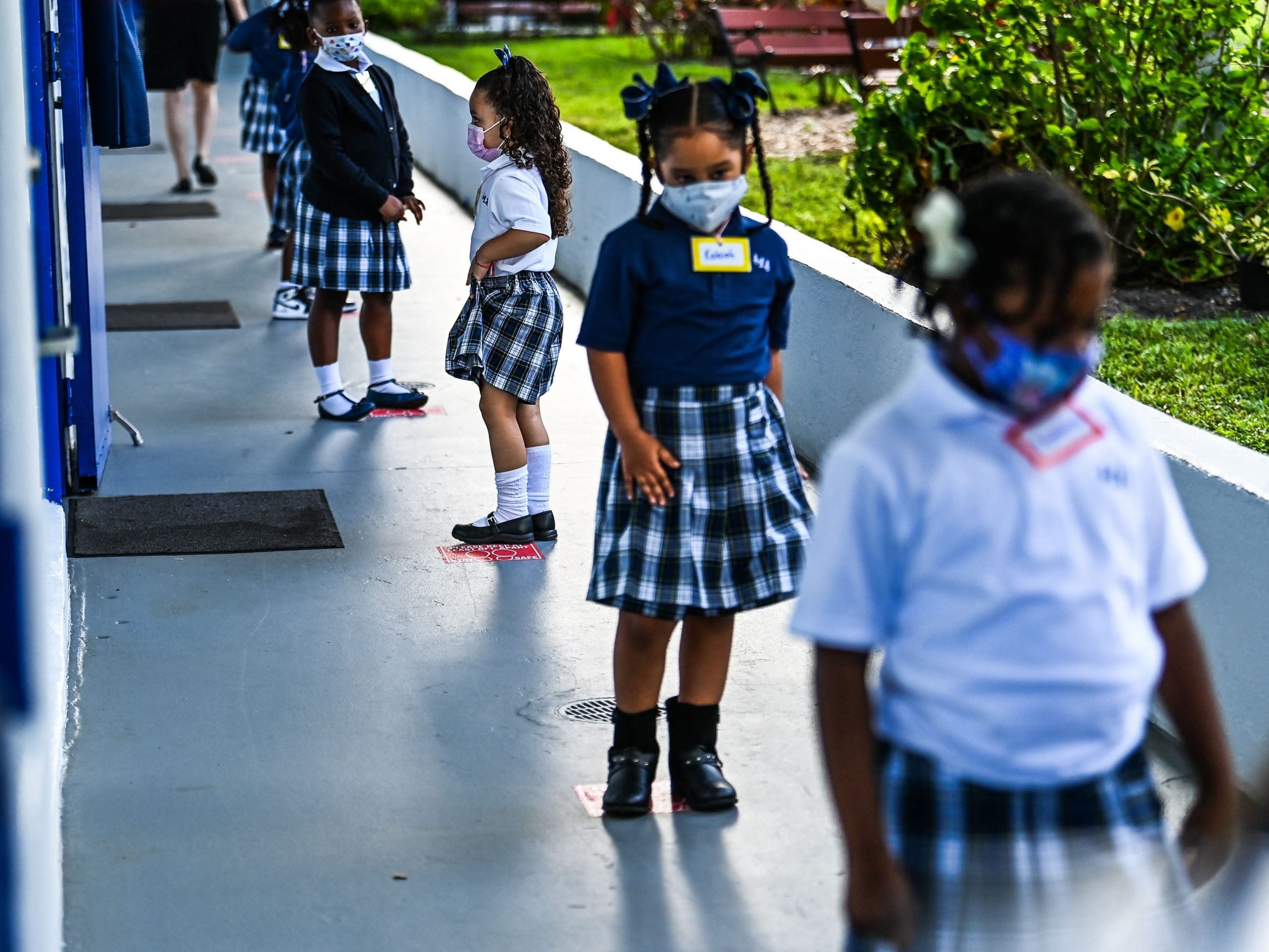 Students wear facemasks and stand in a social distance on their first day of school after summer vacation at the St. Lawrence Catholic School in north of Miami, Florida, on August 18, 2021.