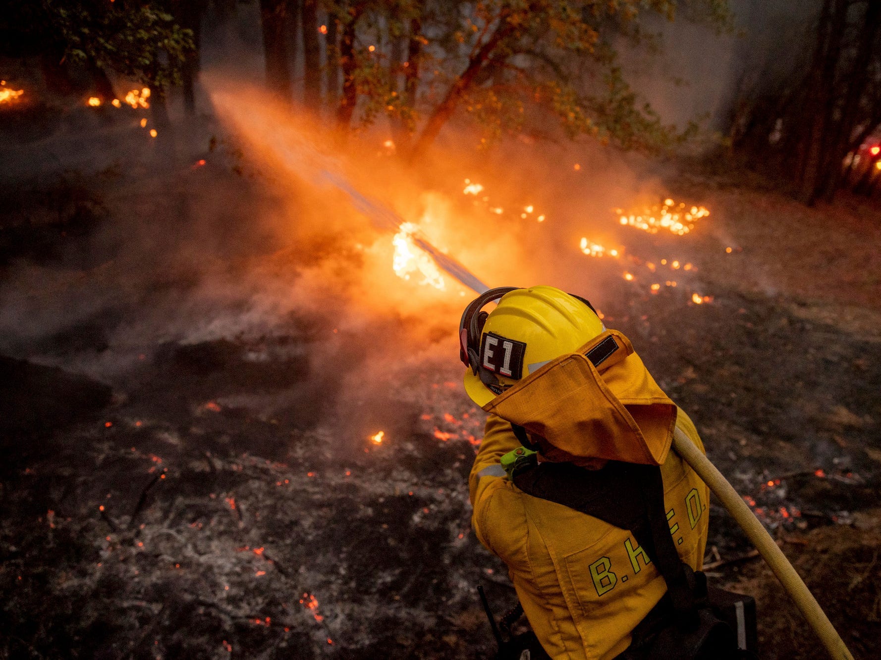 A firefighter hoses down flames from the Dixie Fire in Genesee, Calif., on Saturday, Aug. 21, 2021.