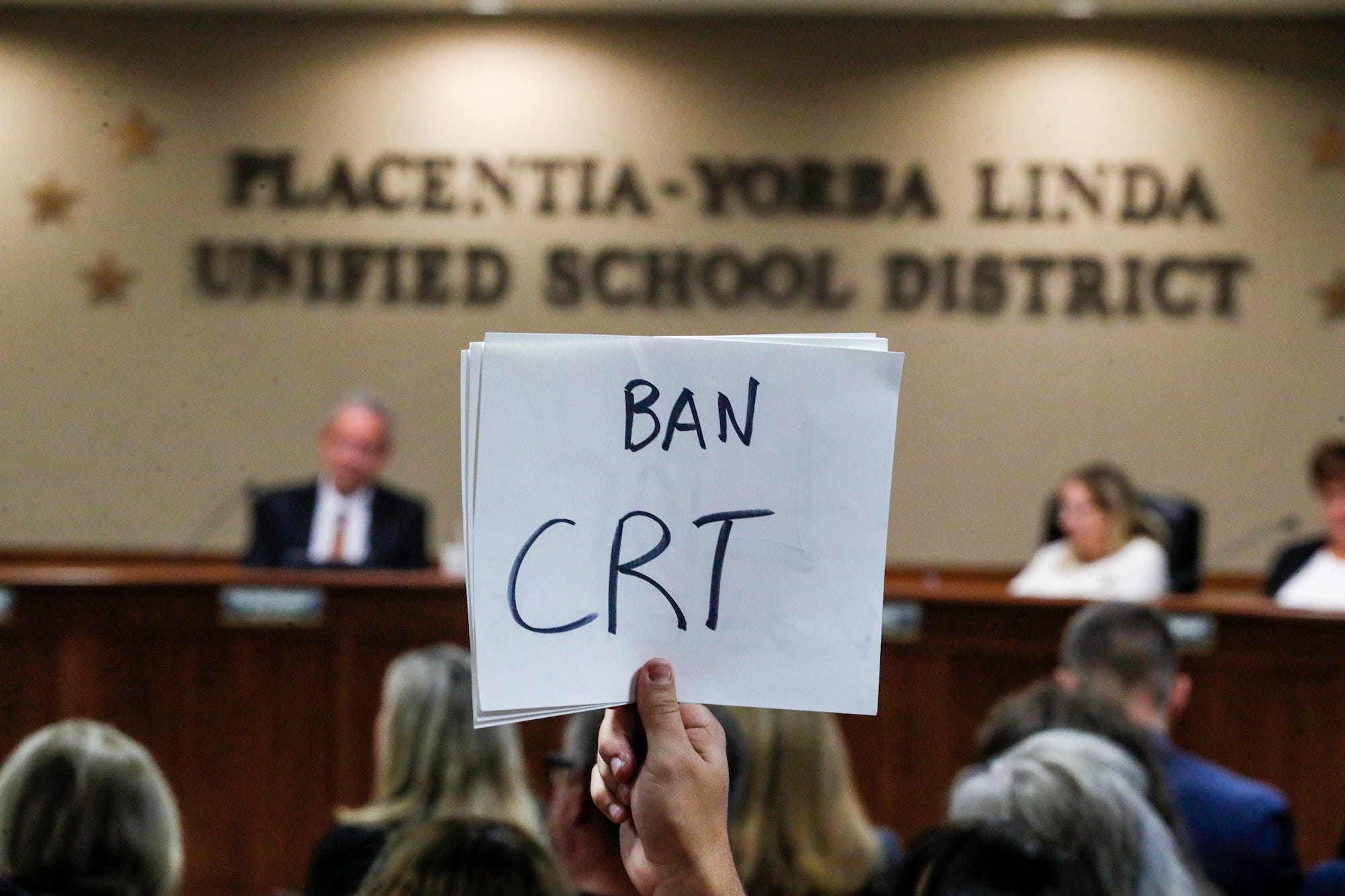 A person at a Placentia-Yorba Linda School Board meeting in California holds up a sign saying 'BAN CRT' in protest of teaching about critical race theory in schools.