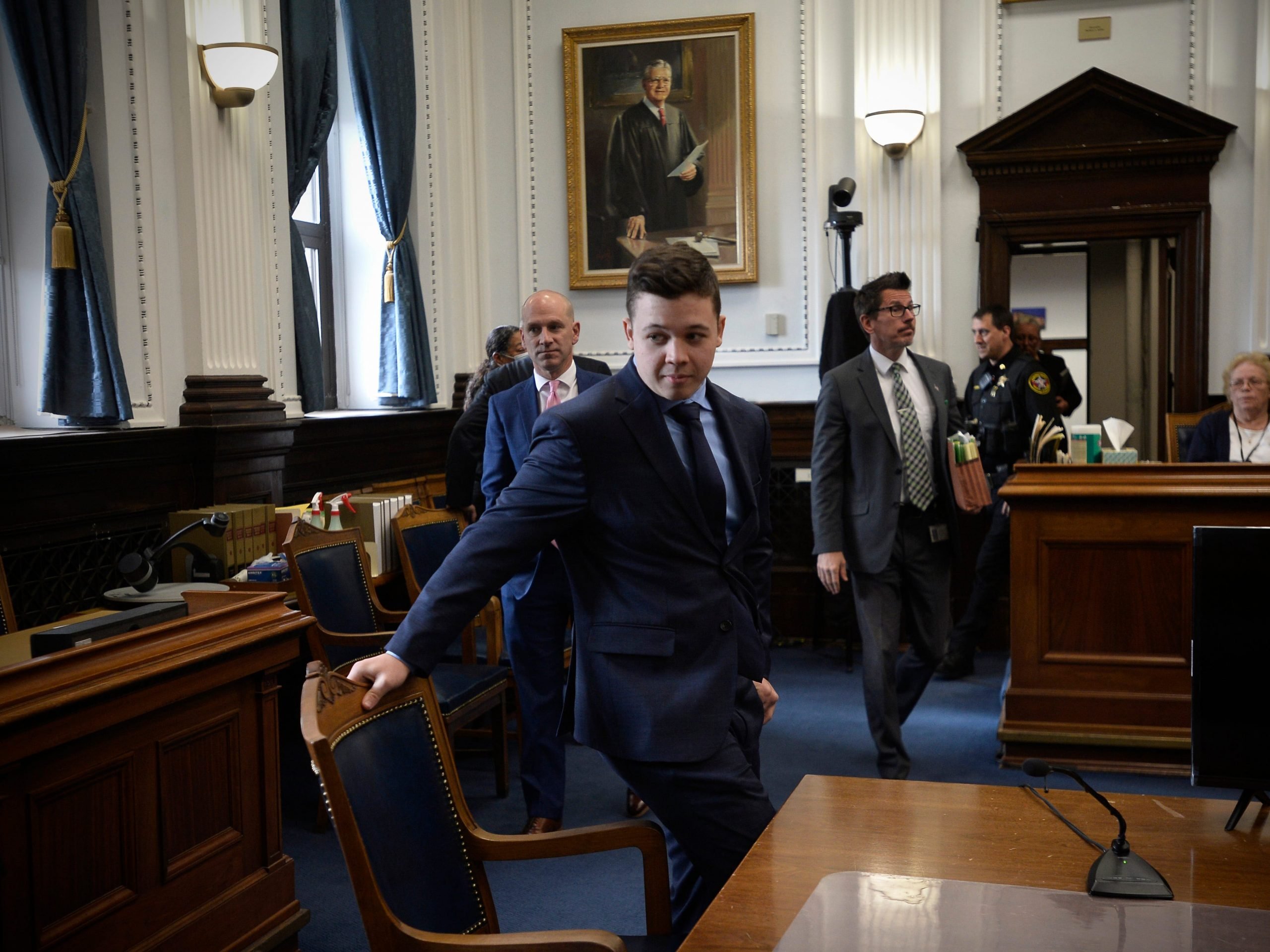 Kyle Rittenhouse, center, pulls out his chair for a meeting Judge Bruce Schroeder called during his trial at the Kenosha County Courthouse on November 18, 2021 in Kenosha, Wisconsin.