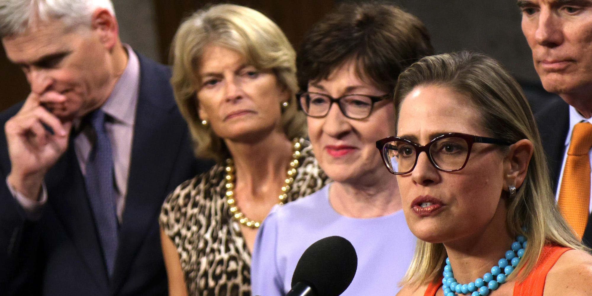 Democratic Sen. Kyrsten Sinema of Arizona speaks as Republican Sens. Lisa Murkowski of Alaska and Susan Collins of Maine stand by on Capitol Hill on July 28, 2021.