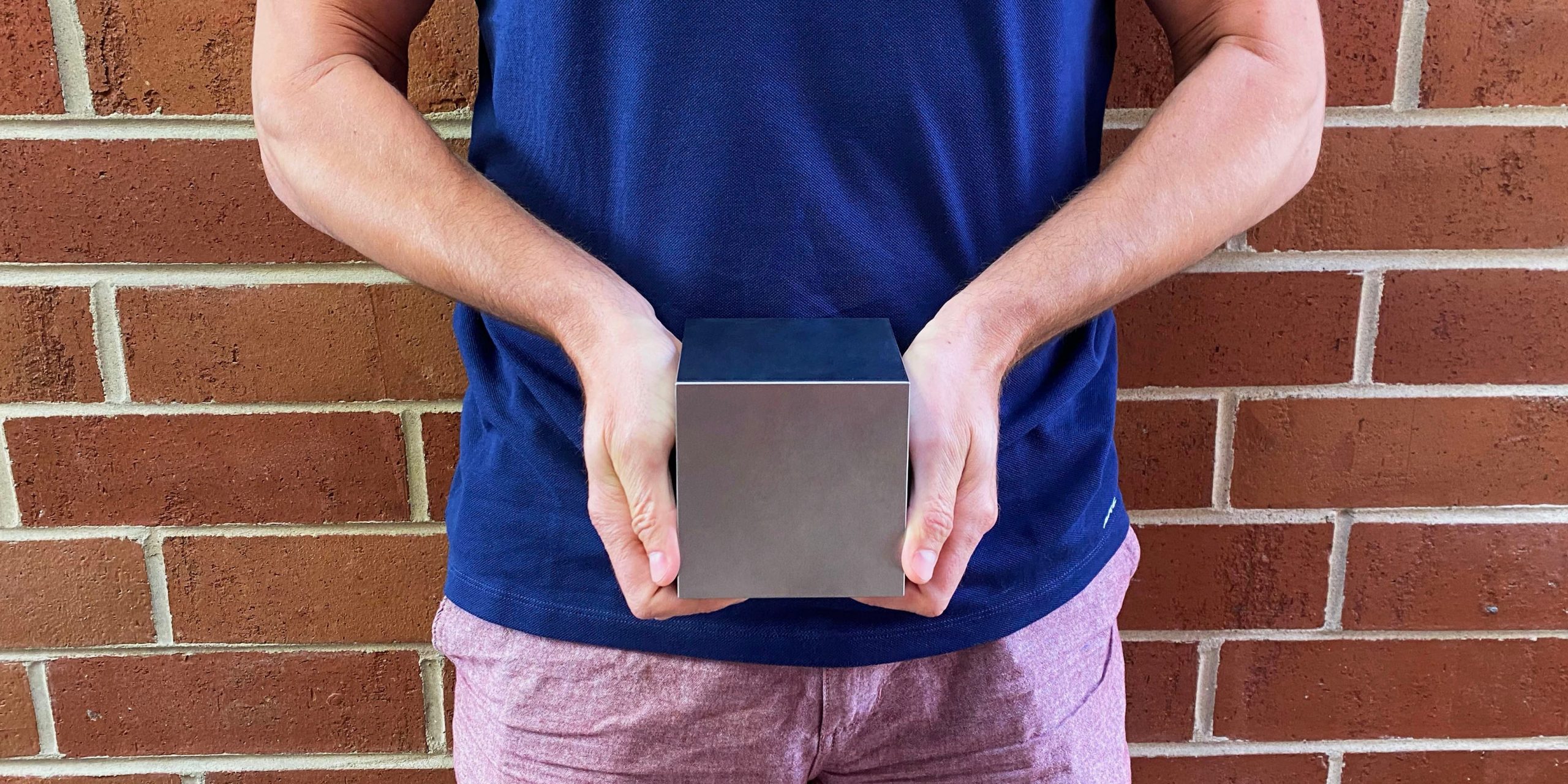 A man holding a four-inch tungsten cube
