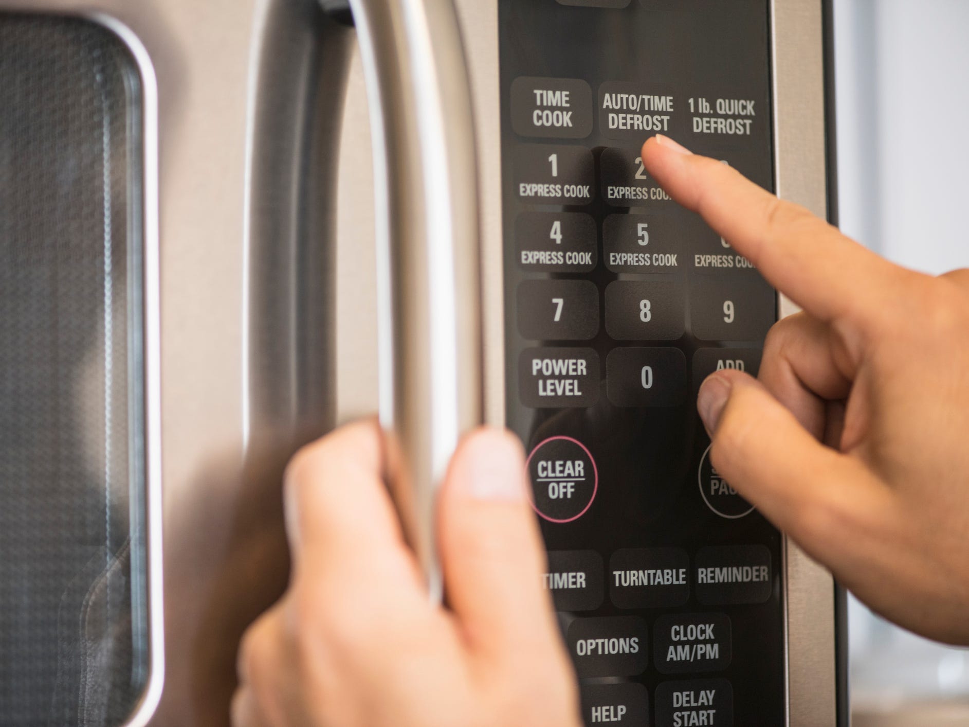 Close up of someone pressing a button on a microwave.