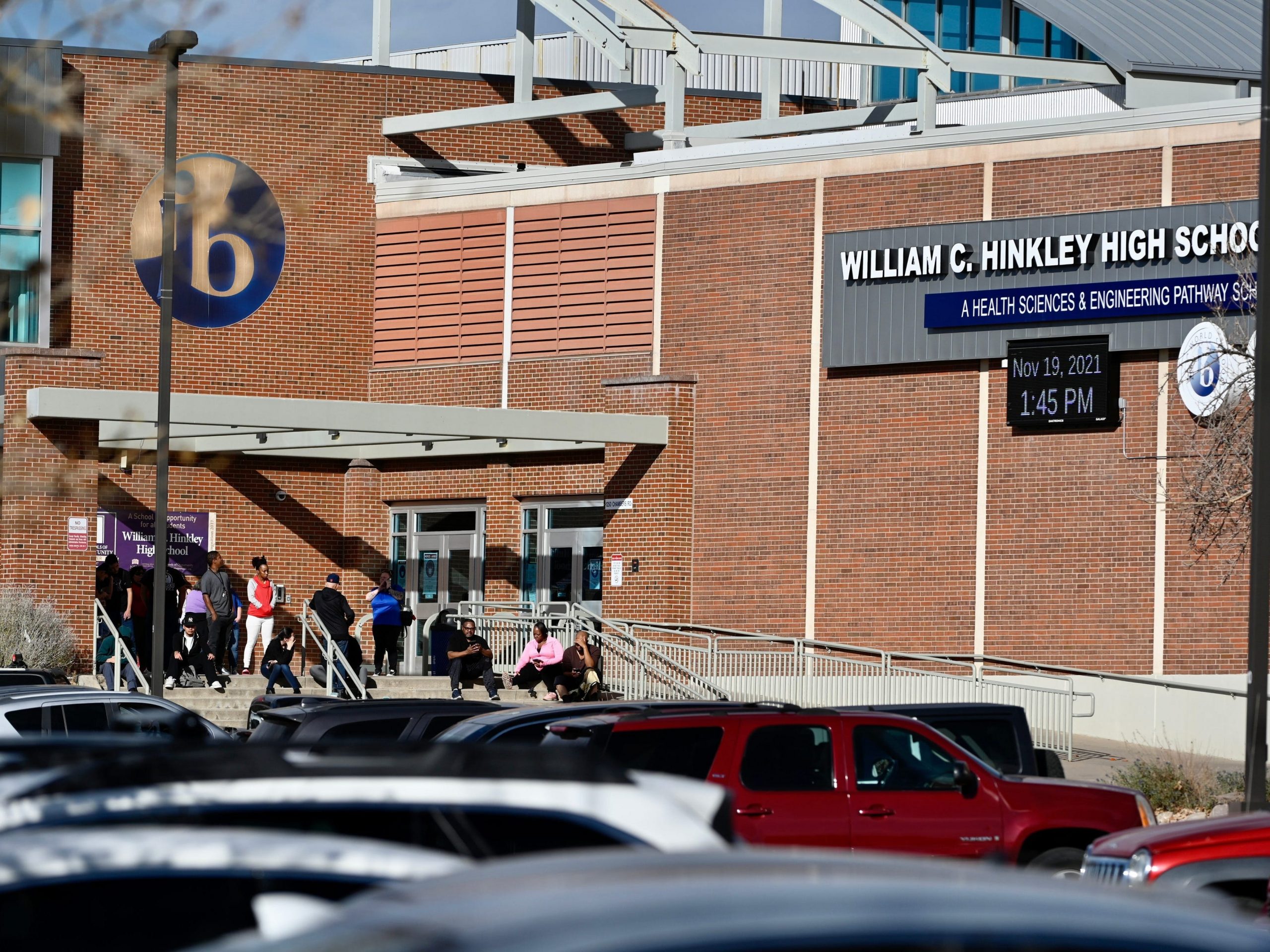 Students and staff gather outside an entrance to the school after a shooting in the parking lot of Hinkley High School in Aurora, Colorado on Friday, November 19, 2021.