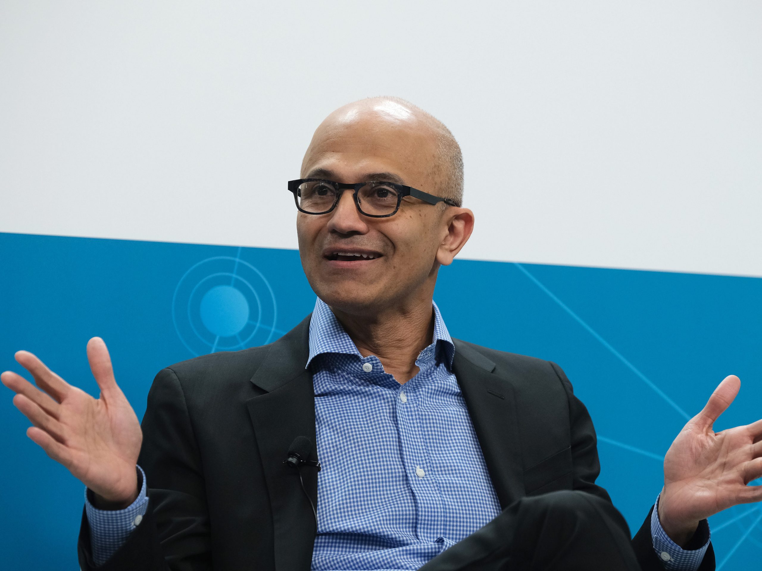 Microsoft CEO Satya Nadella, seated with open hands.