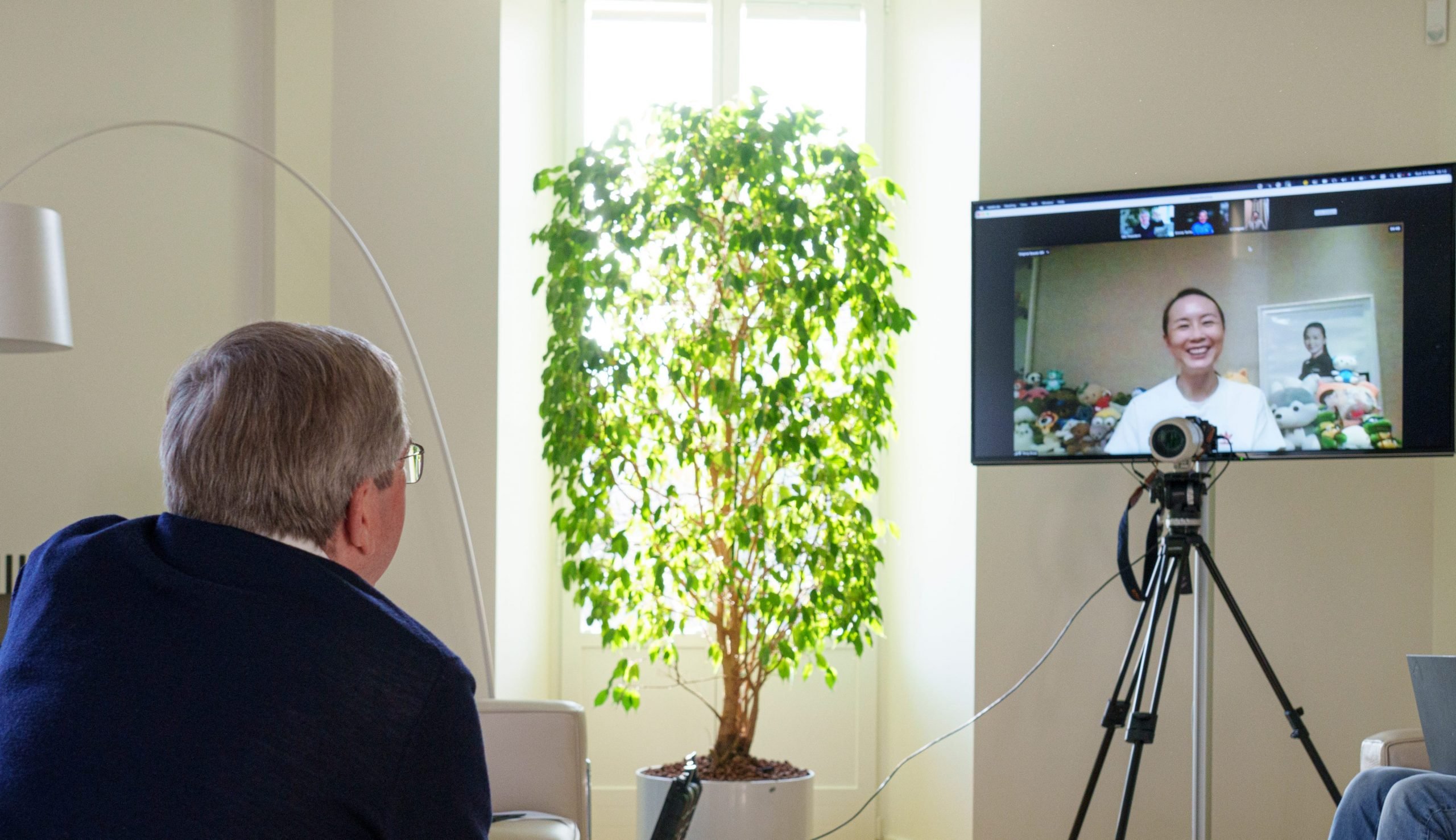 A man turned away from the camera, looking at a screen with a woman smiling.