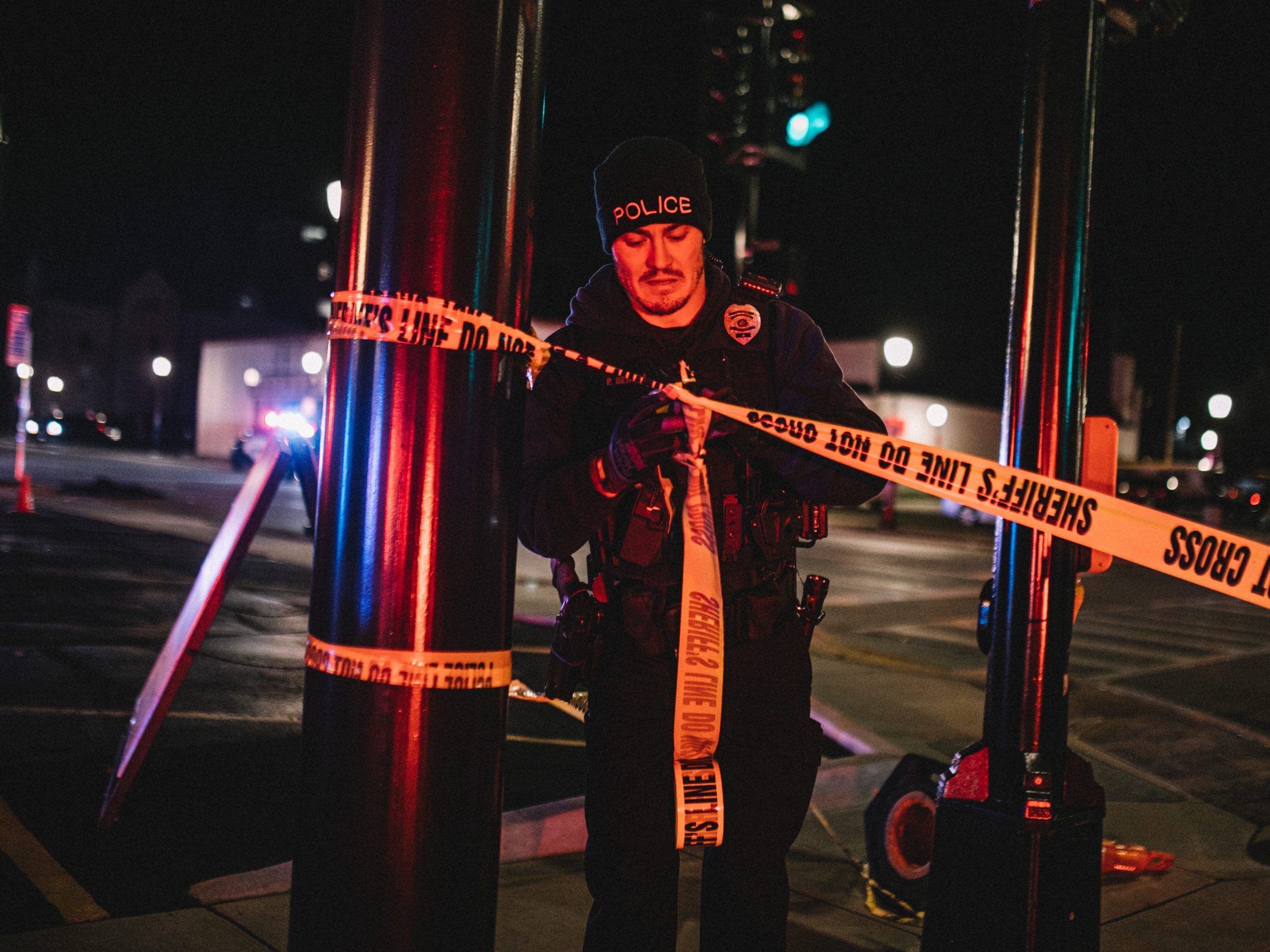 police officer ties up yellow police tape