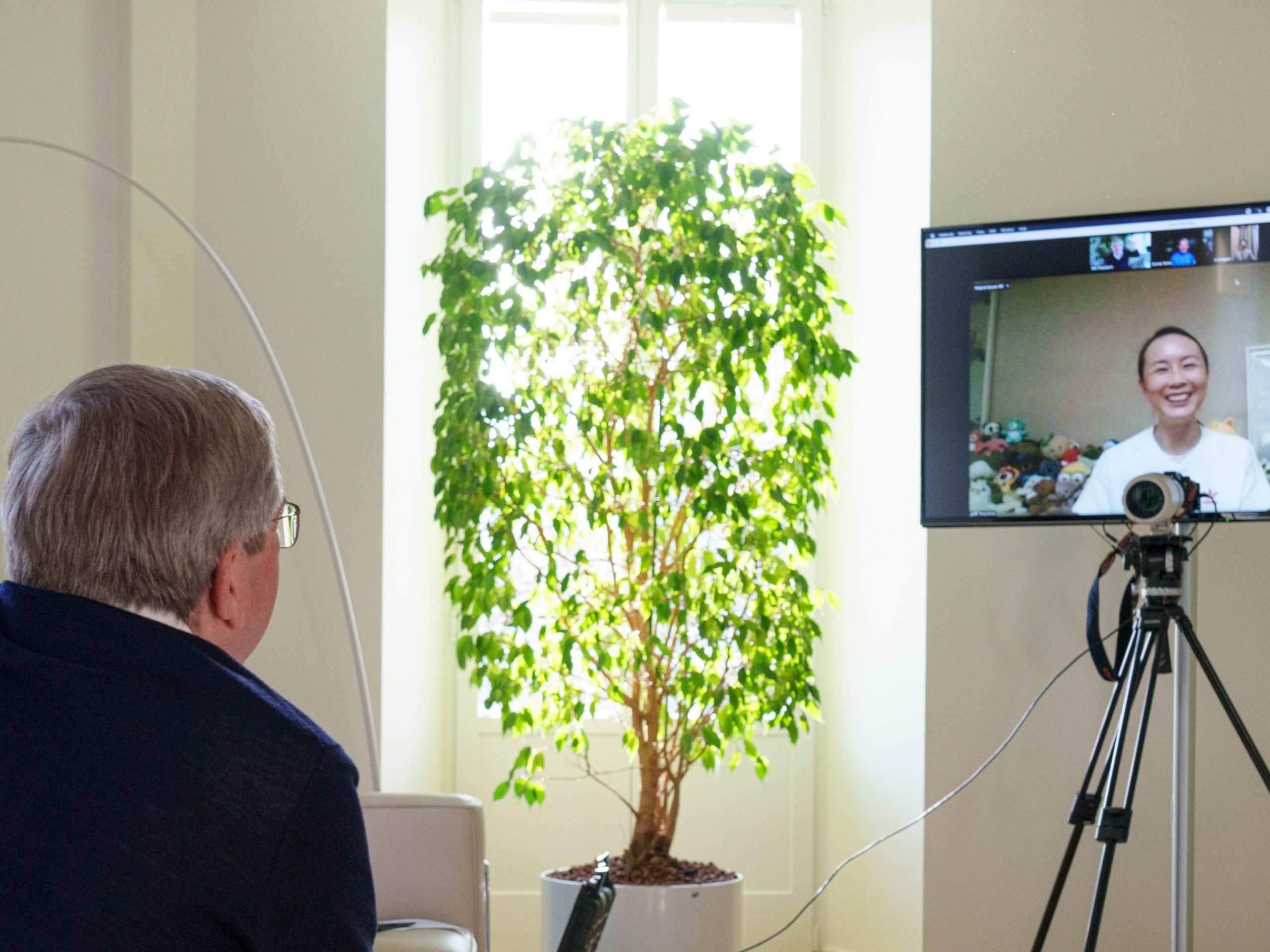 A man turned away from the camera, looking at a screen with a woman smiling.