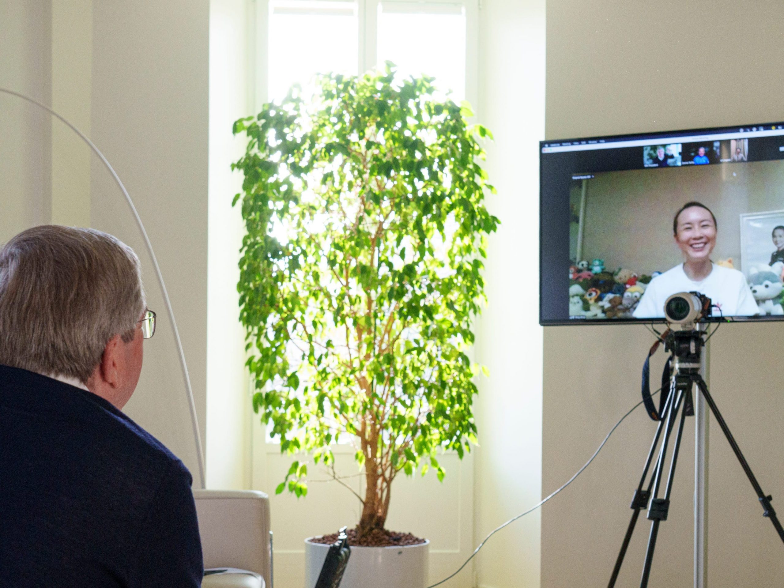 A man turned away from the camera, looking at a screen with a woman smiling.