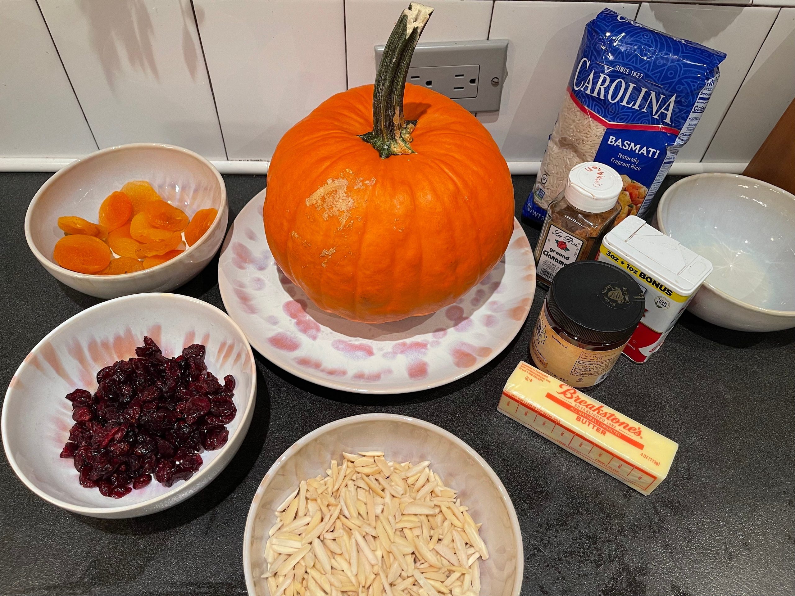 Dried fruits, a pumpkin, rice, butter, honey, nuts, and cinnamon.