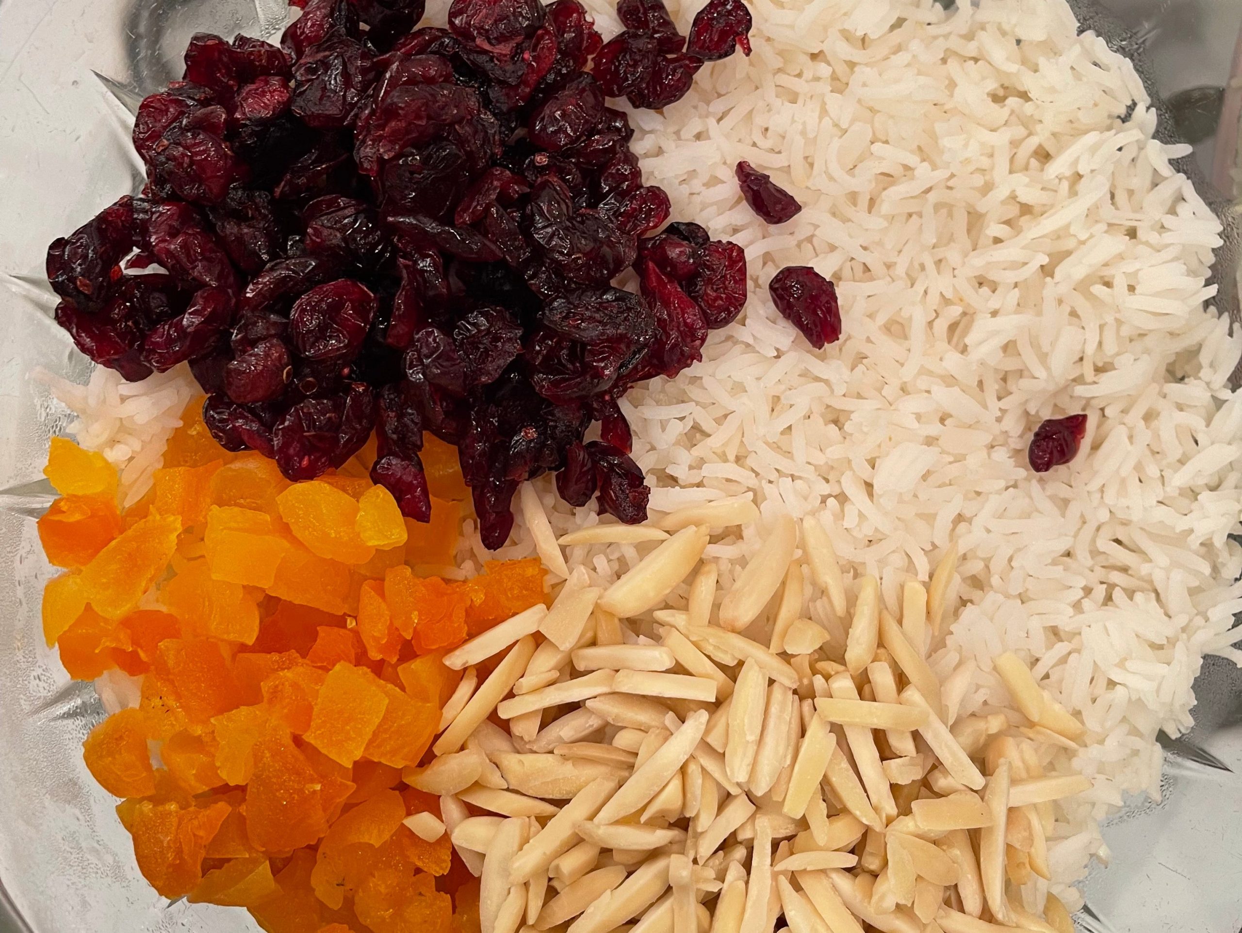 Chopped apricots, cranberries, and pine nuts in a bowl with rice.