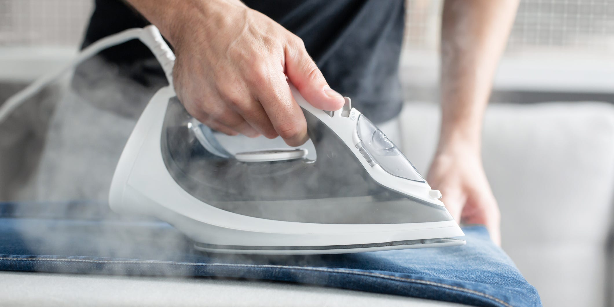 A closeup of a hand ironing a pair of jeans