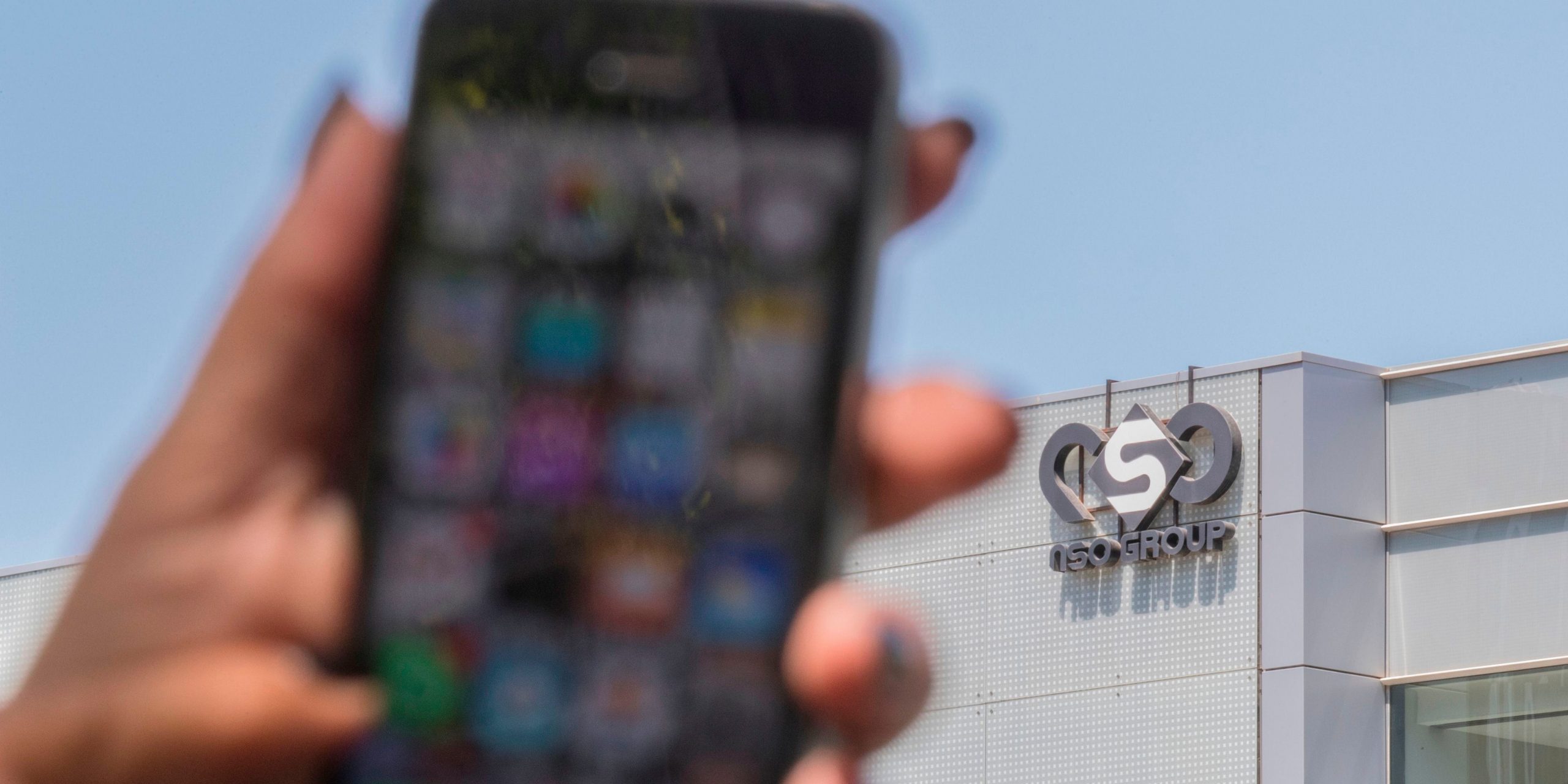 Woman holds phone outside NSO Group in Herzliya
