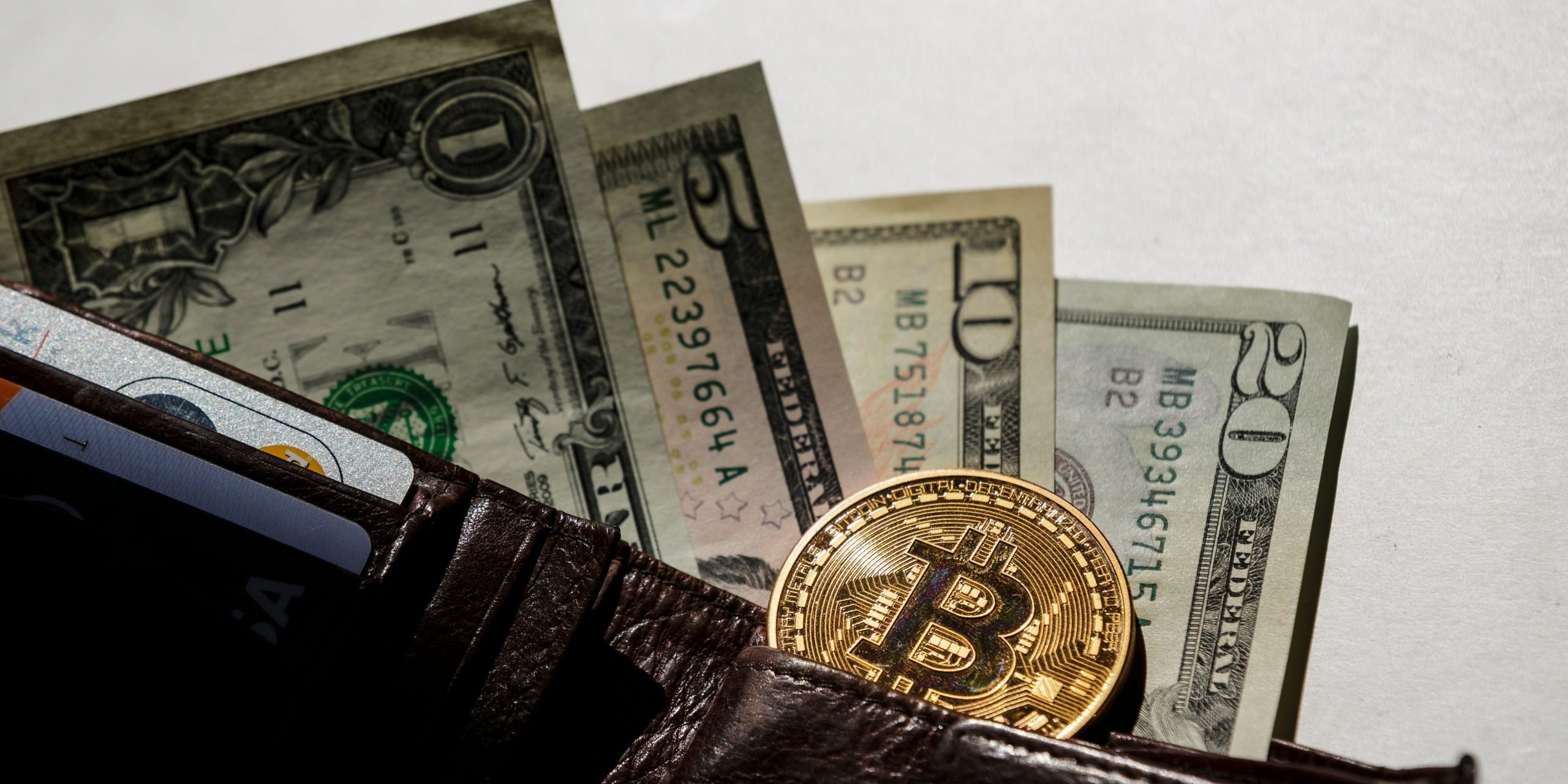 Dollar bills and a Bitcoin put in a wallet on August 14, 2015, in Berlin, Germany.