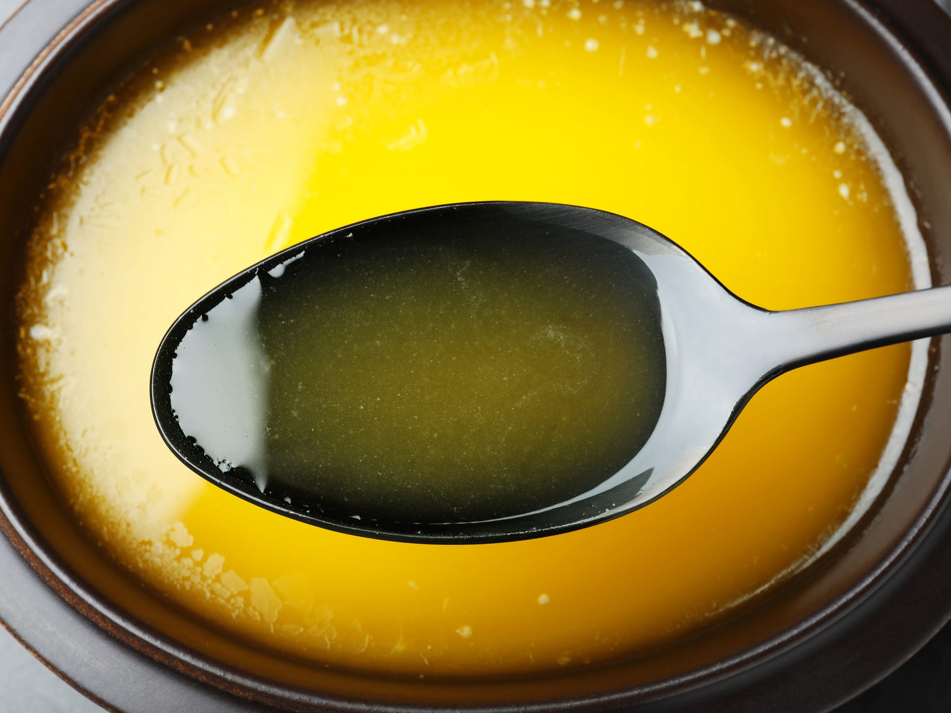 Spoon of clarified butter over bowl.