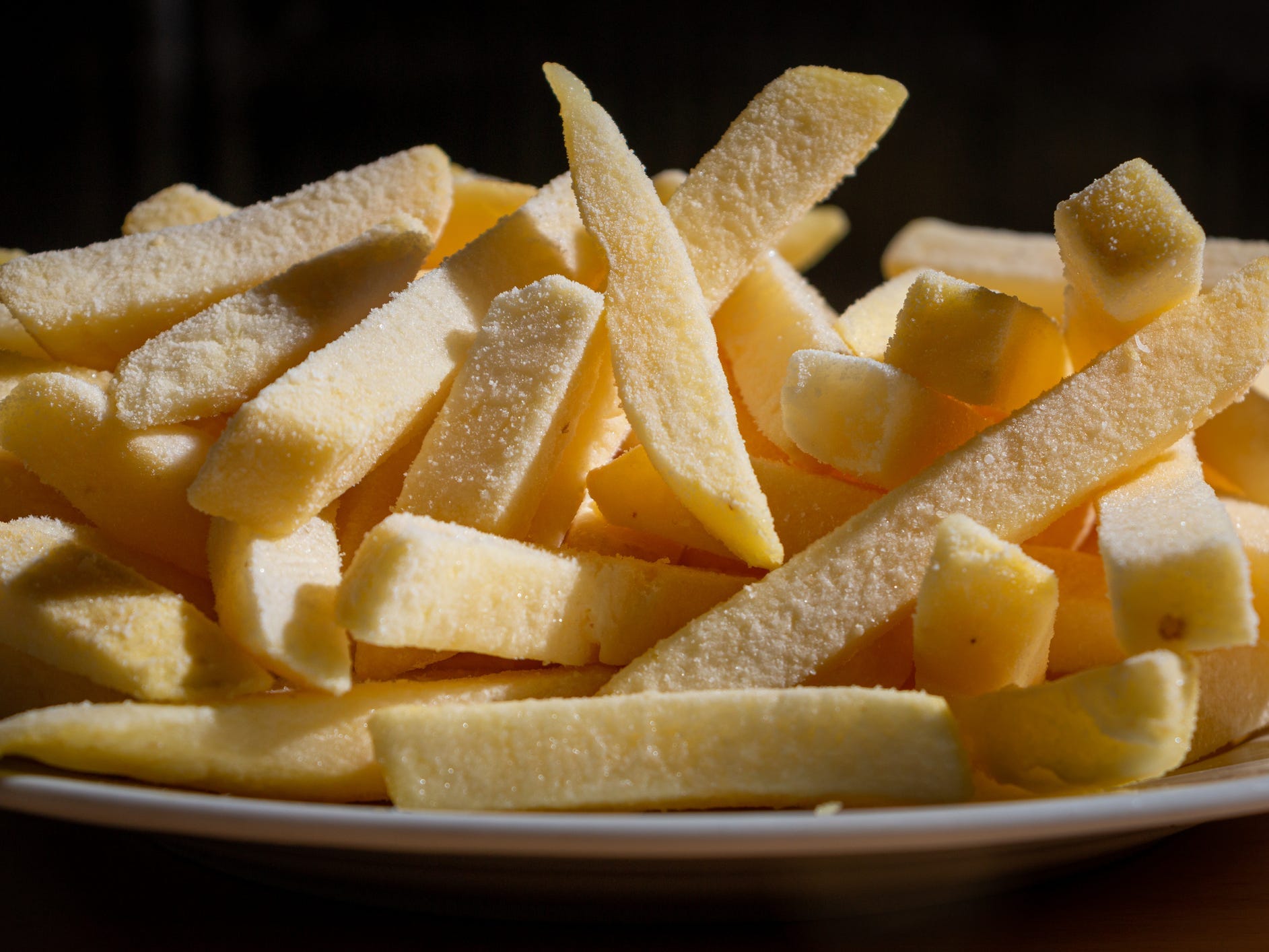 Frozen sliced potato fries on a plate.