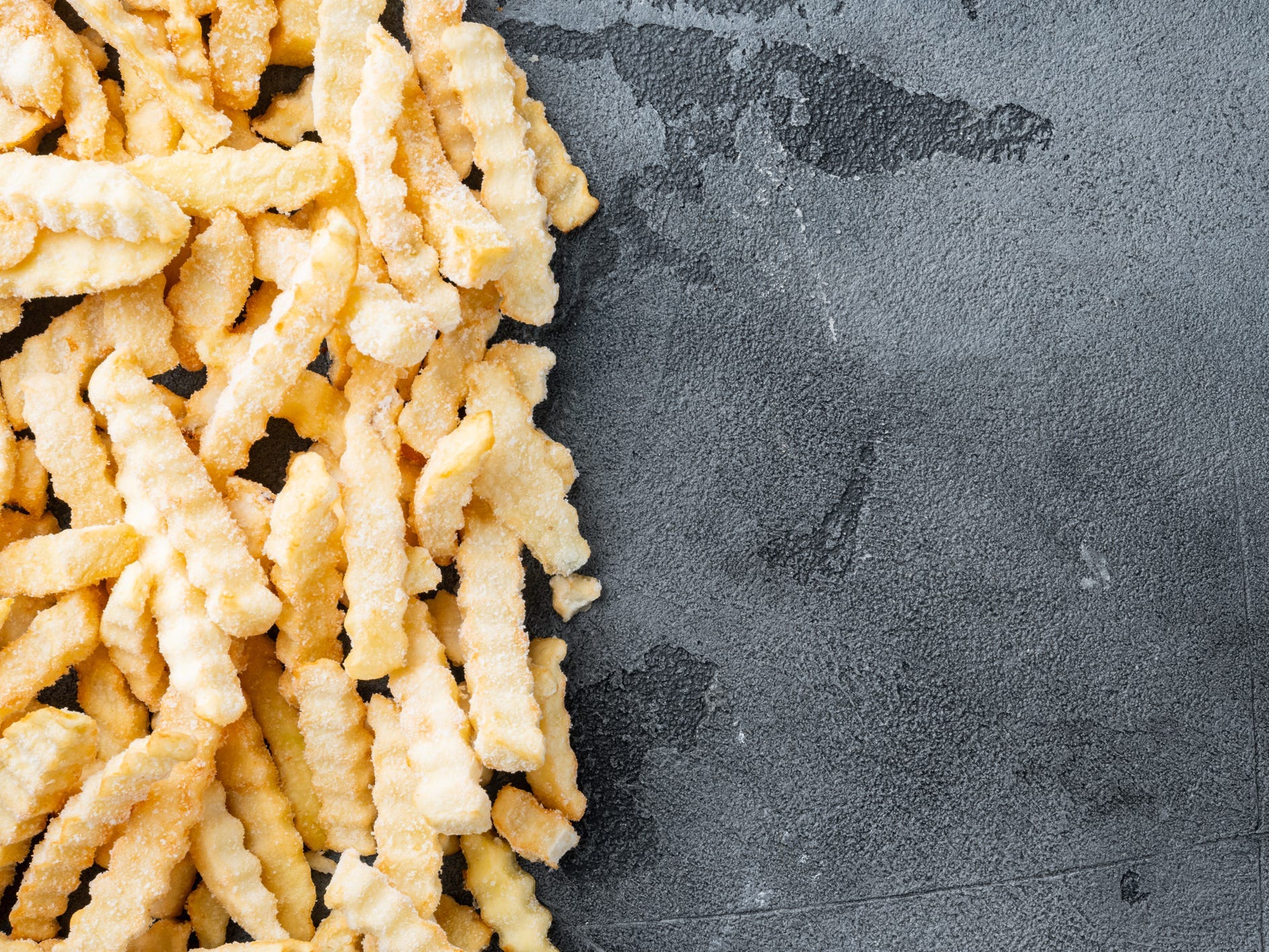 Frozen crinkle oven fries on a gray background.