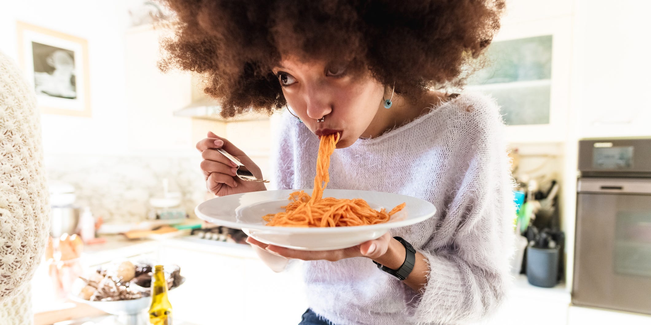 Woman slurping noodles from a plate.