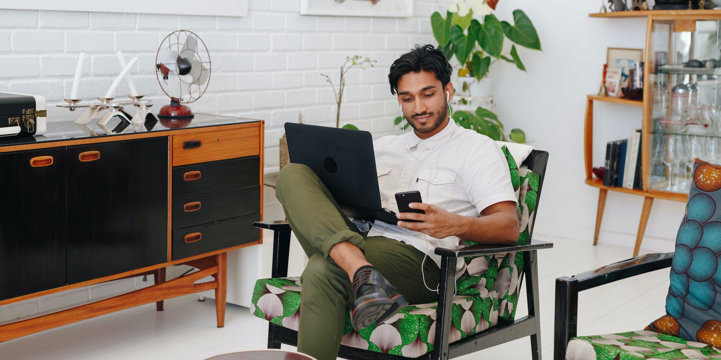 man using laptop and phone at home