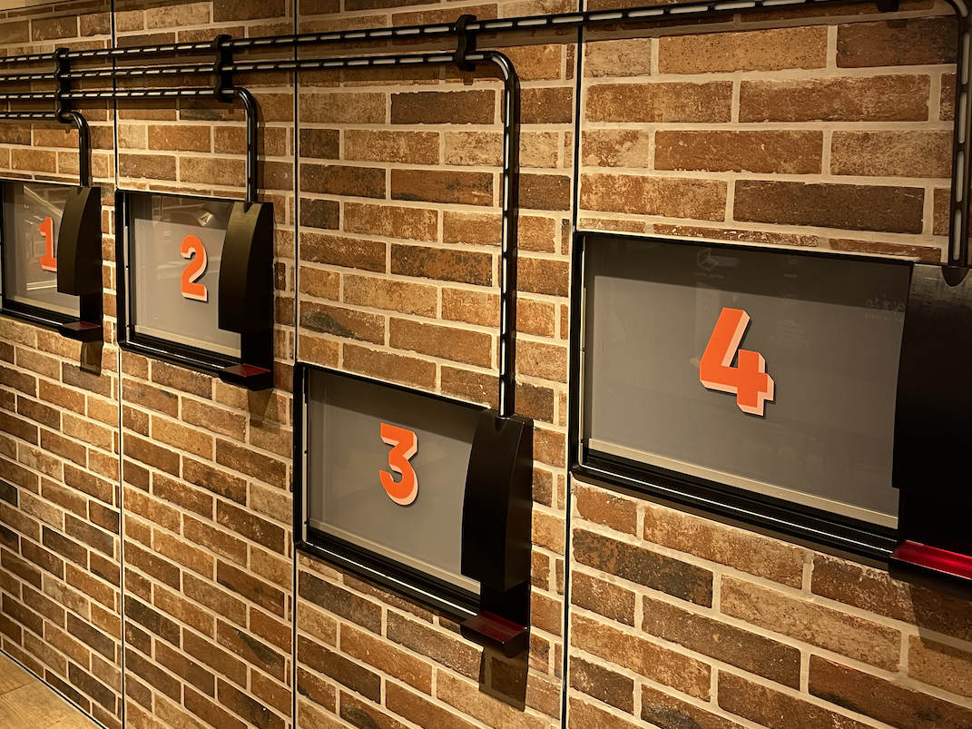 Image of pizzeria brick wall with doors marked 1, 2, 3, and 4 on them in red lettering