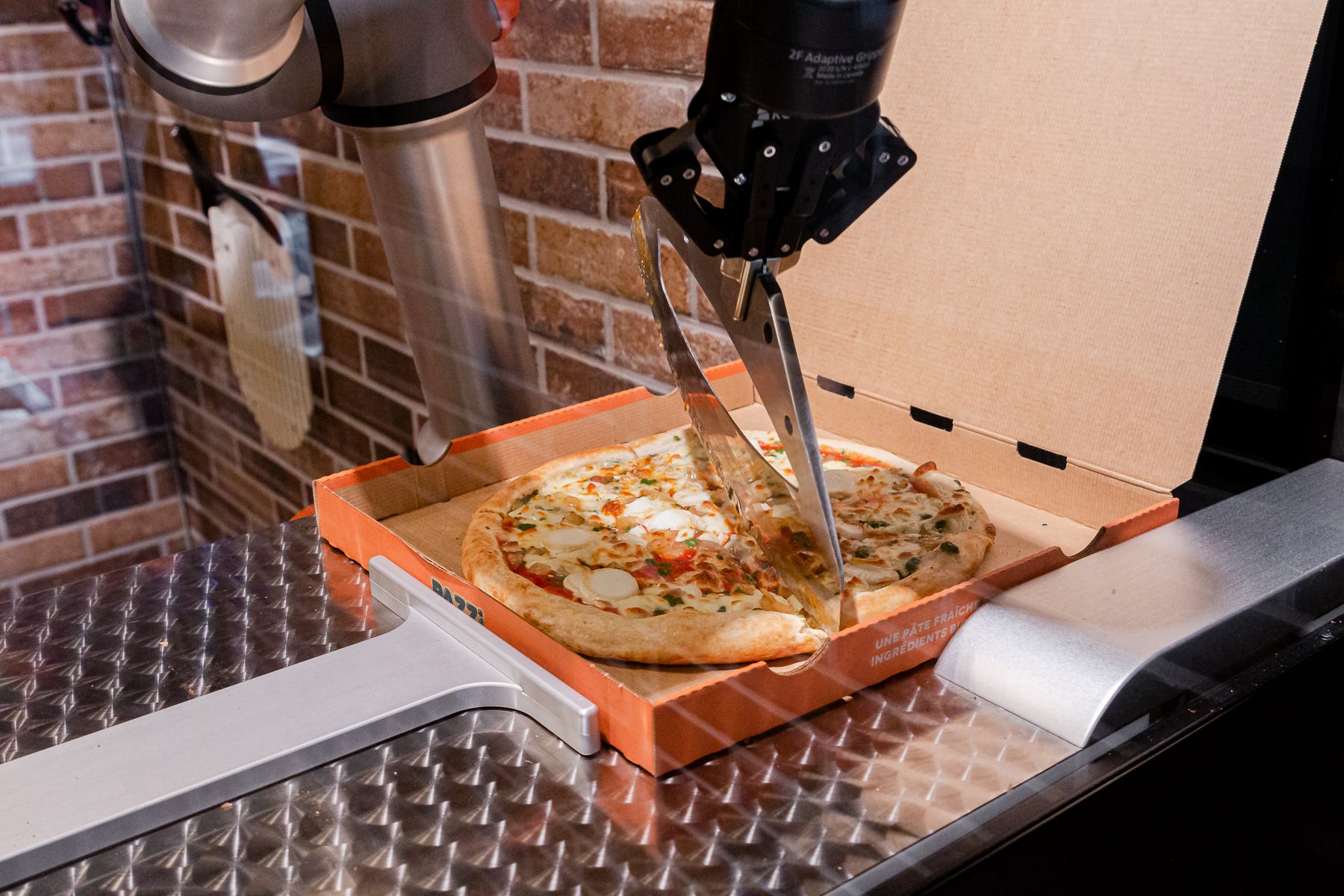 Robot arm with a slicer cutting pizza into slices