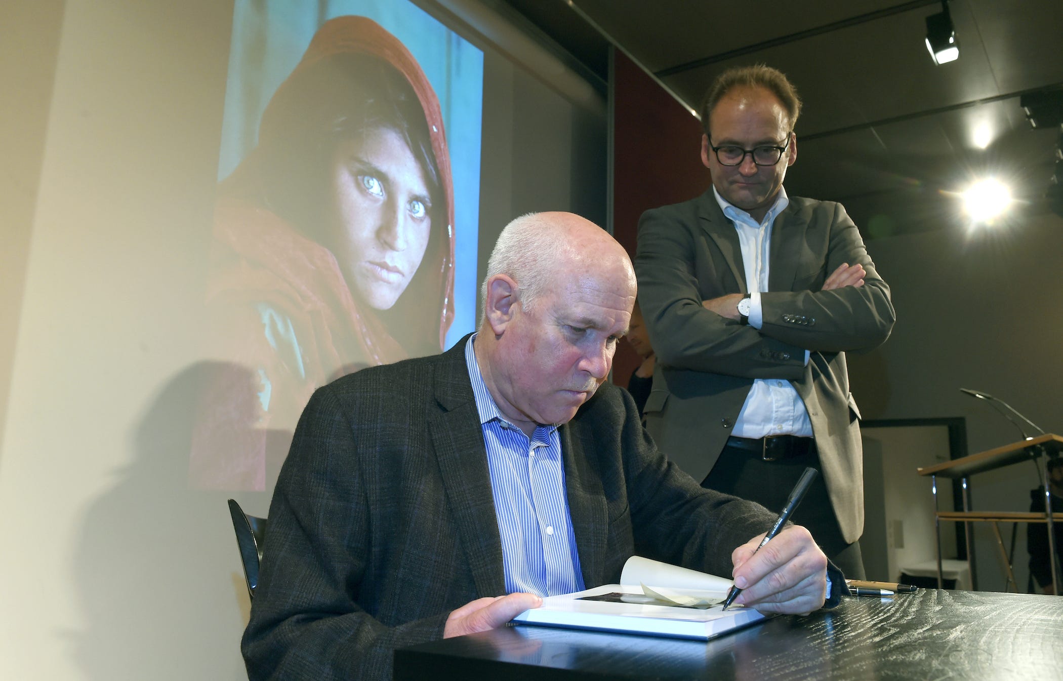 photographer steve mccurry seated, signing a book
