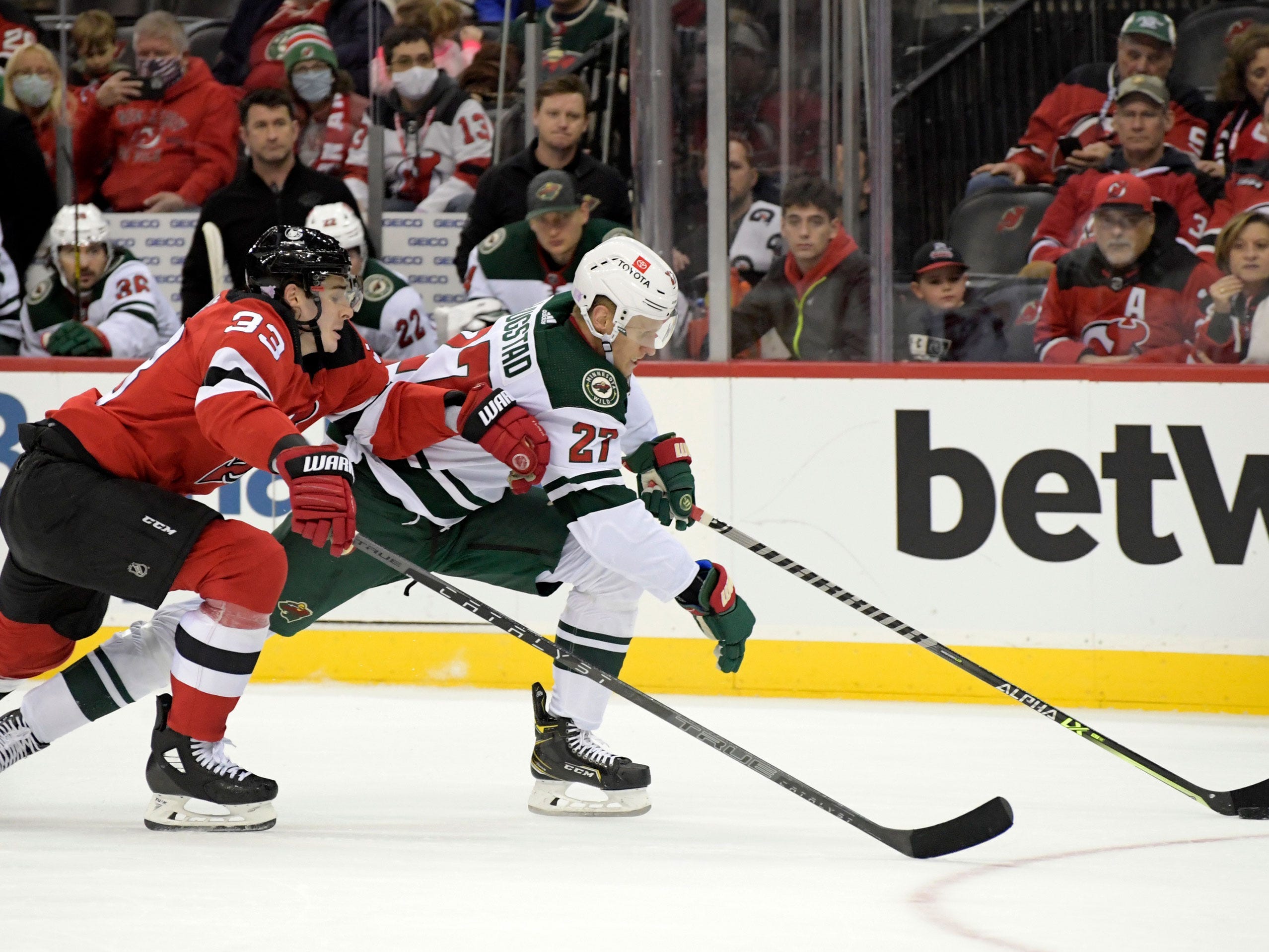 Minnesota Wild center Nick Bjugstad skates with the puck as he is pursued by New Jersey Devils defenseman Ryan Graves.