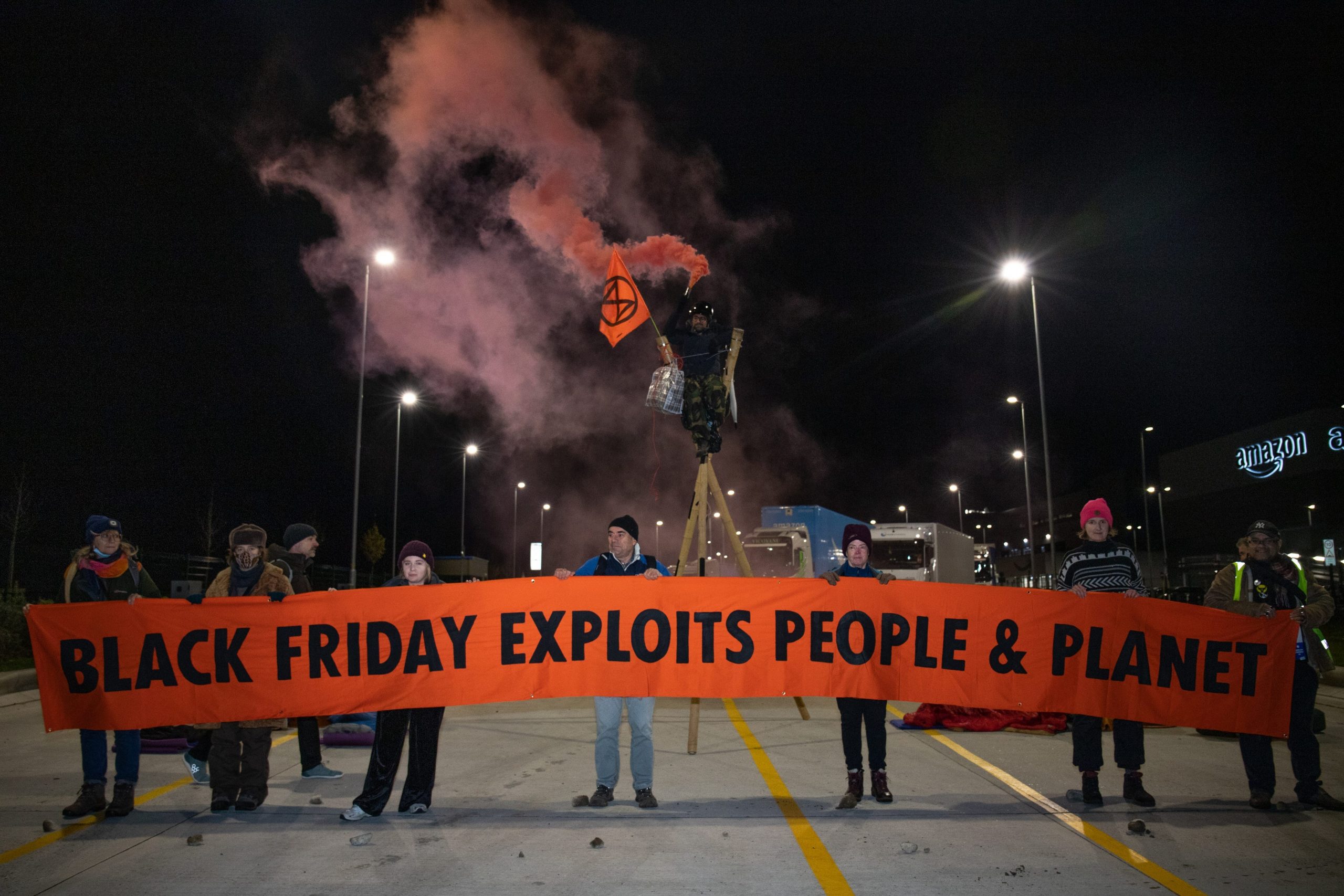 Extinction Rebellion protesters hold up a banner that says "Black Friday exploits people and planet" outside an Amazon facility in Dartford, UK.