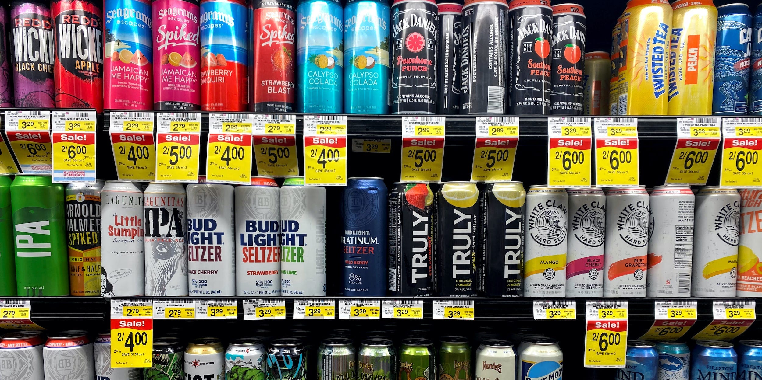 Rows of cans of hard seltzer and beer on shelf in store