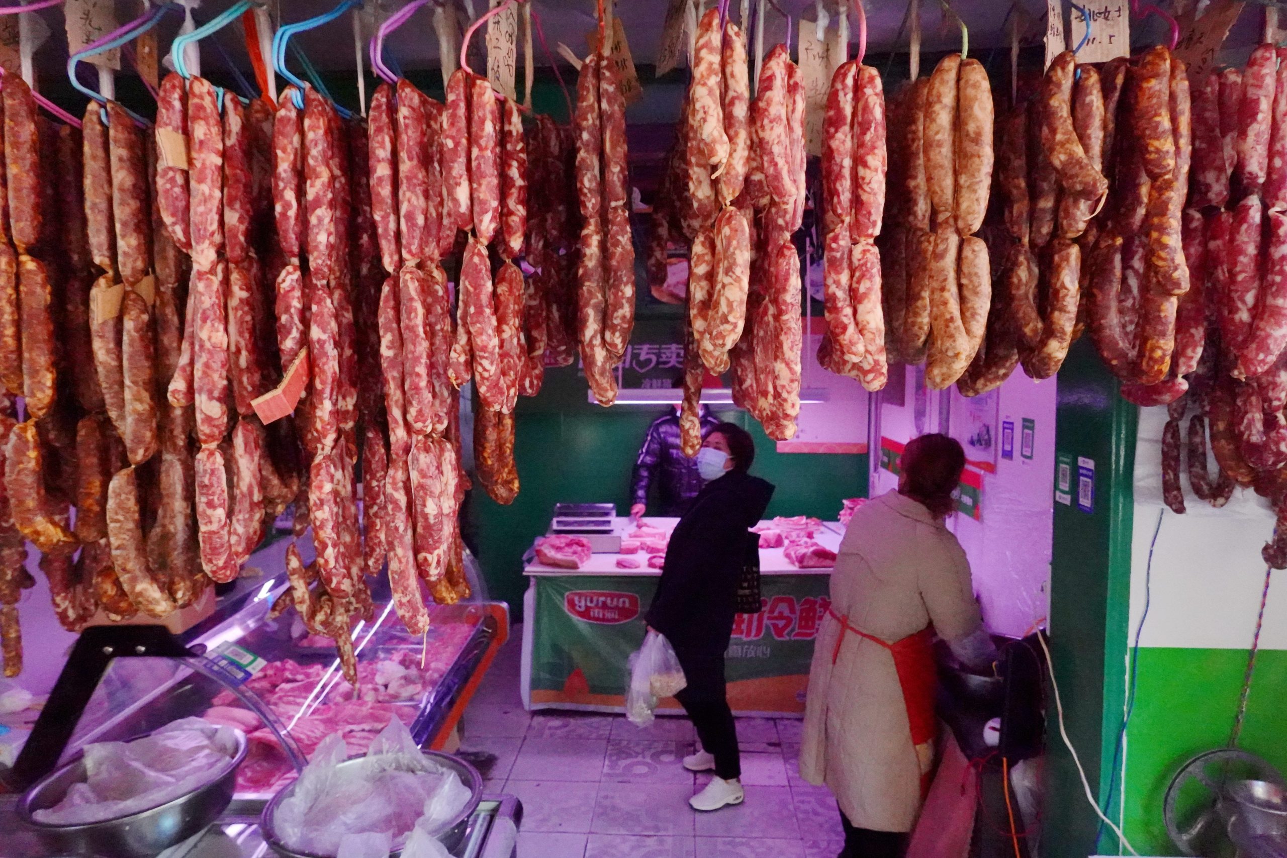 Sausages hanging in foreground at a butcher shop in China.