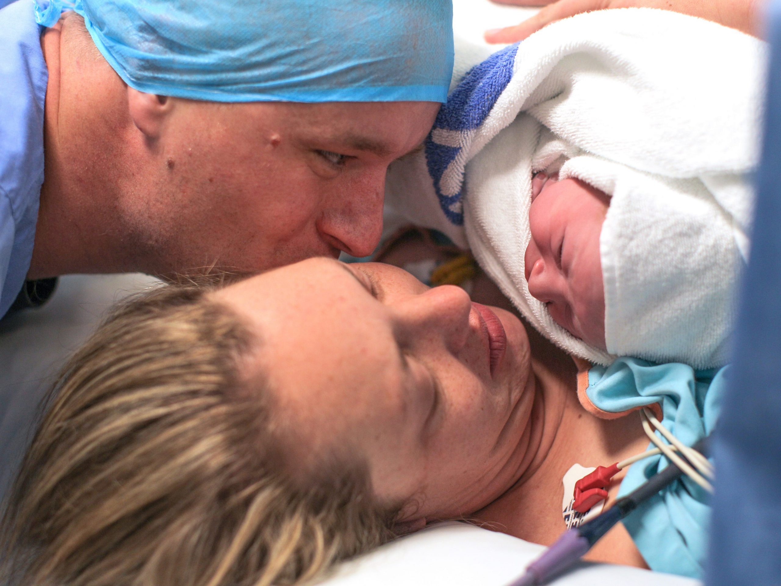 a husband and wife hold their newborn baby boy for the first time.