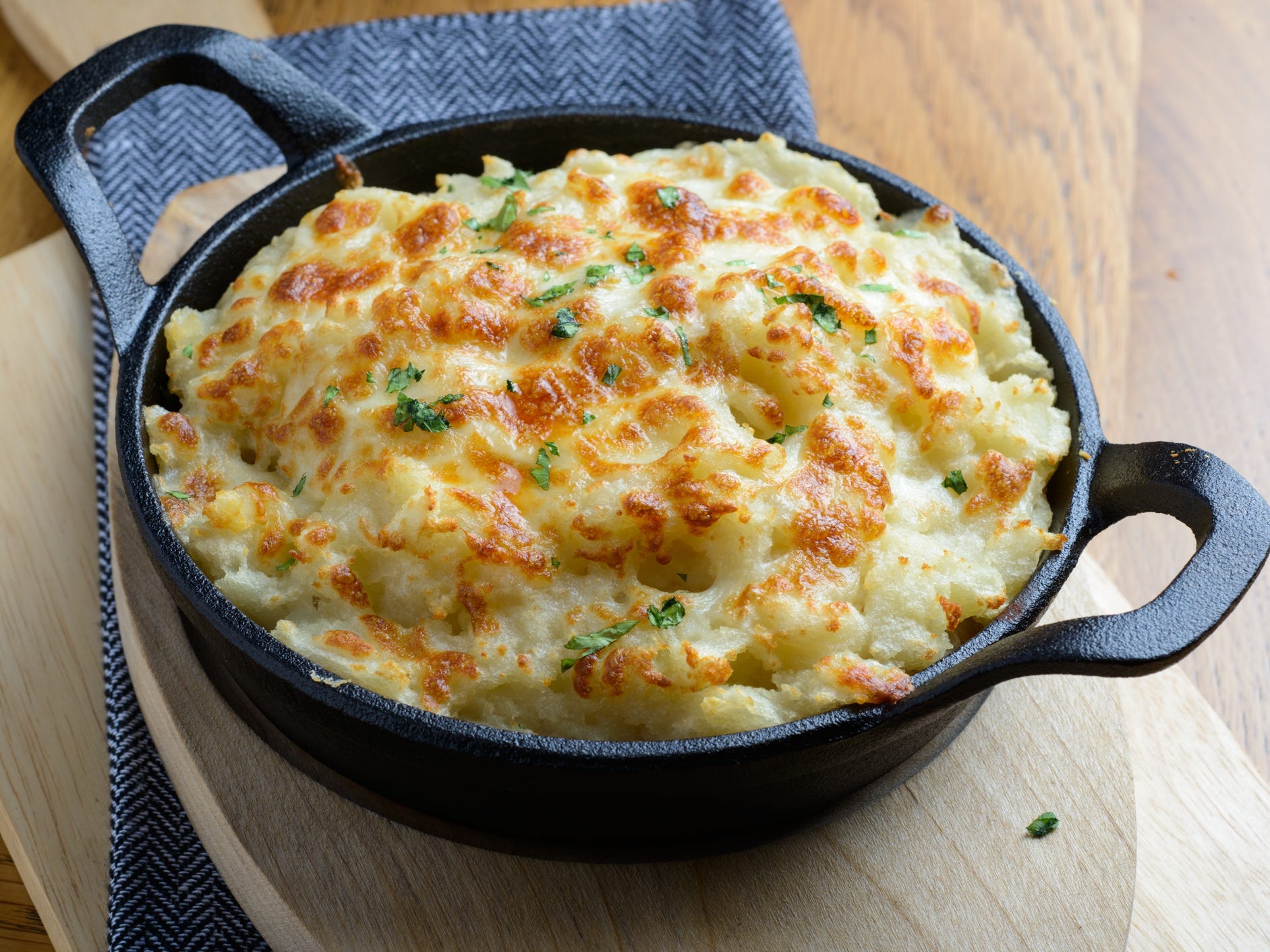 A cast-iron skilled of baked mashed potatoes with a golden top