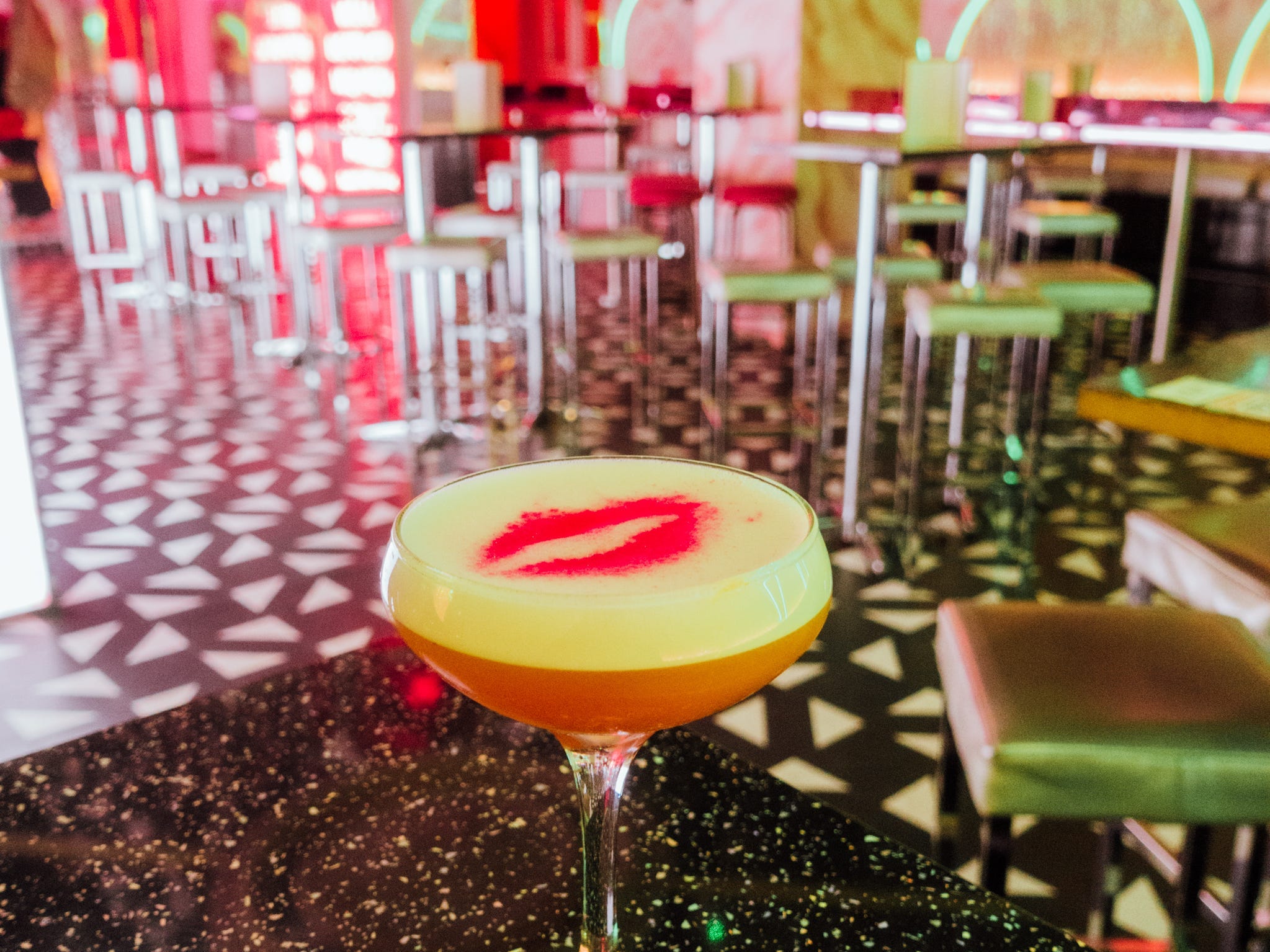 A cocktail surrounded by neon signs at Tonight Josephine in London.