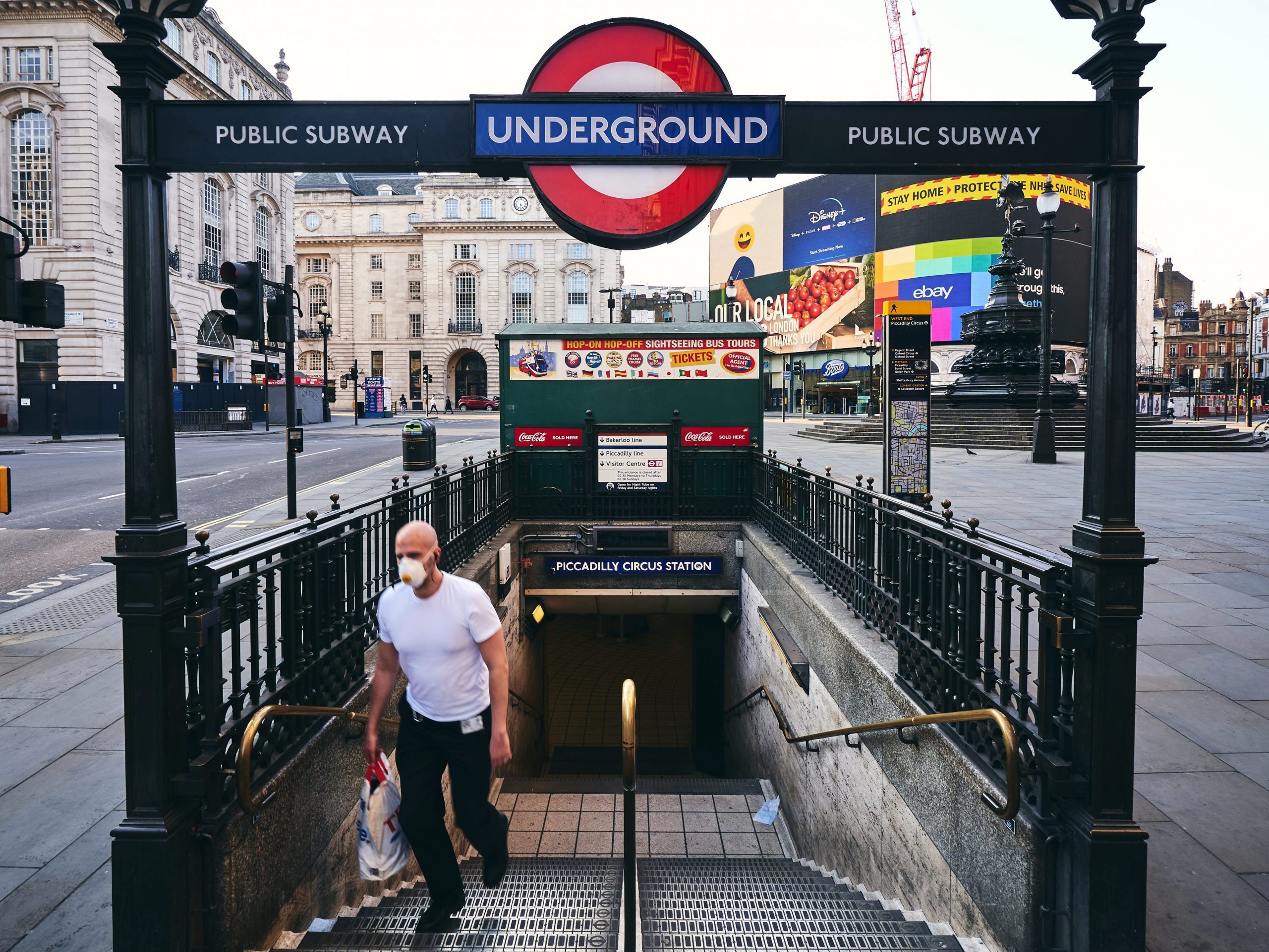 A person leaving the Piccadilly Circus subway underground metro stop while wearing a medical face mask during COVID-19.