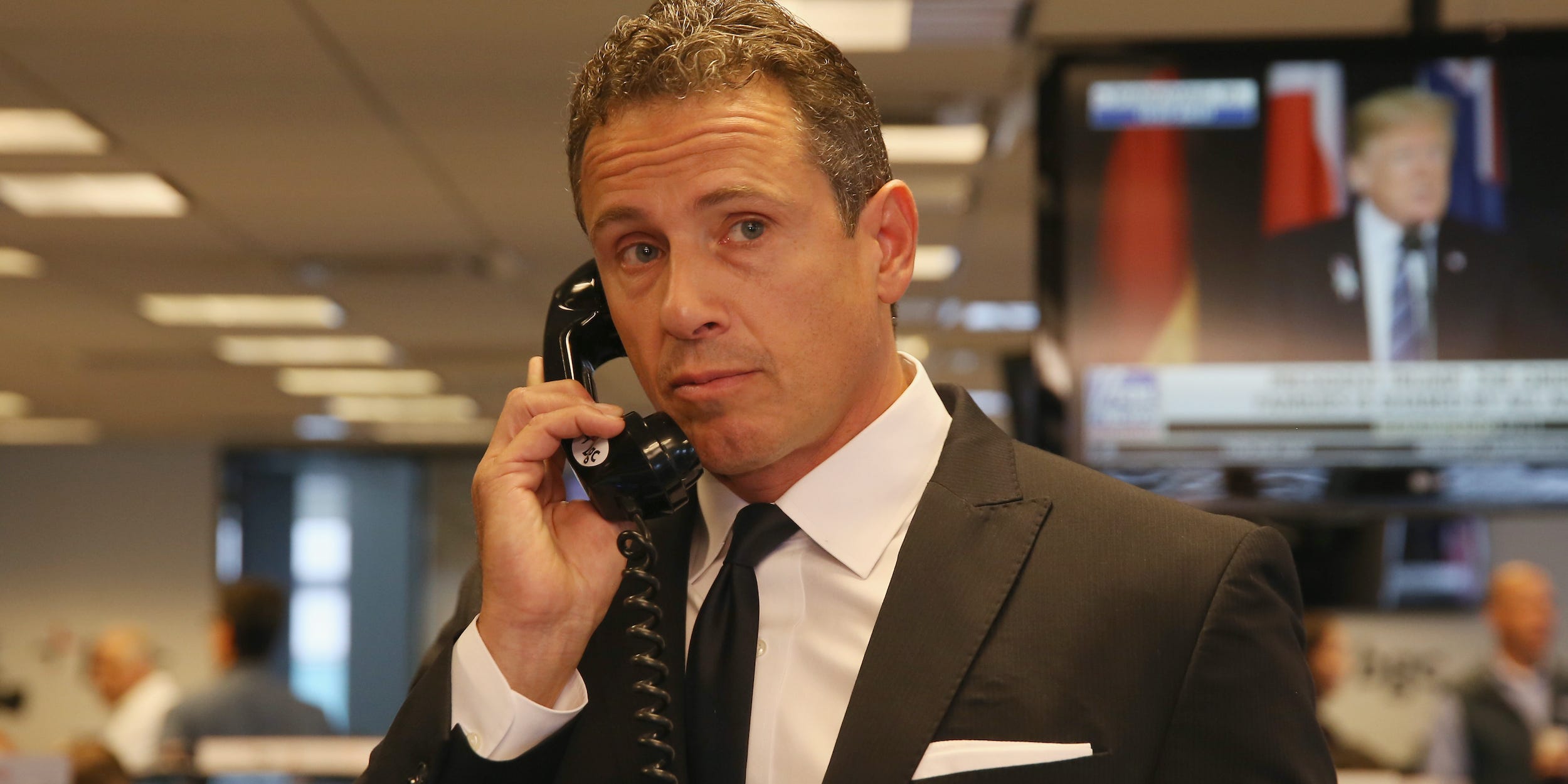 Chris Cuomo holds a landline phone to his ear, looking off to his left.