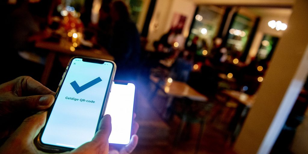 Bezoekers van een café moeten voor binnenkomst hun QR-code scannen.