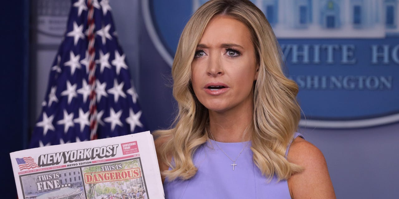 Former White House press secretary Kayleigh McEnany holds up a copy of the New York Post in the briefing room.