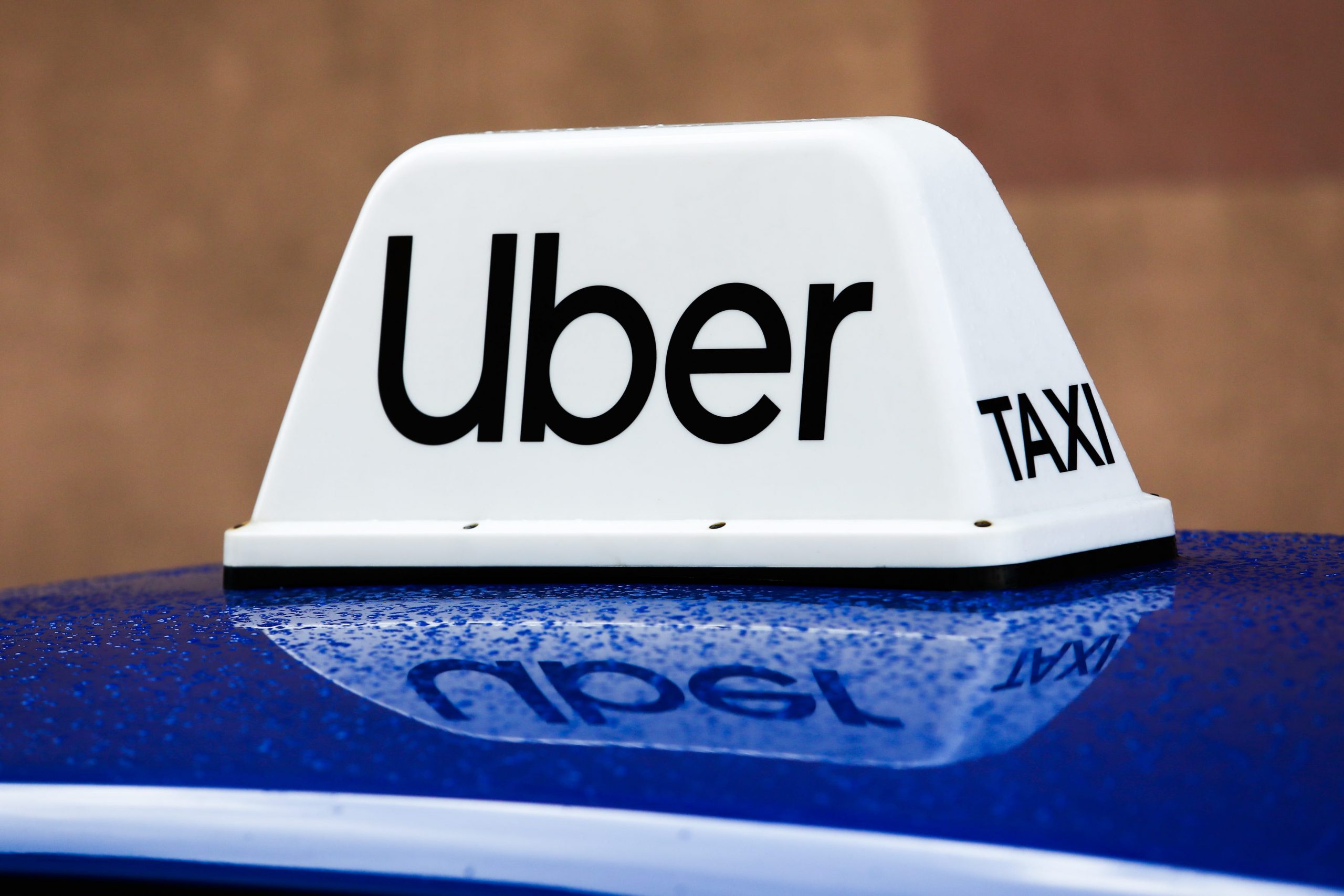 An Uber logo on a white sign attached to a bright blue car roof