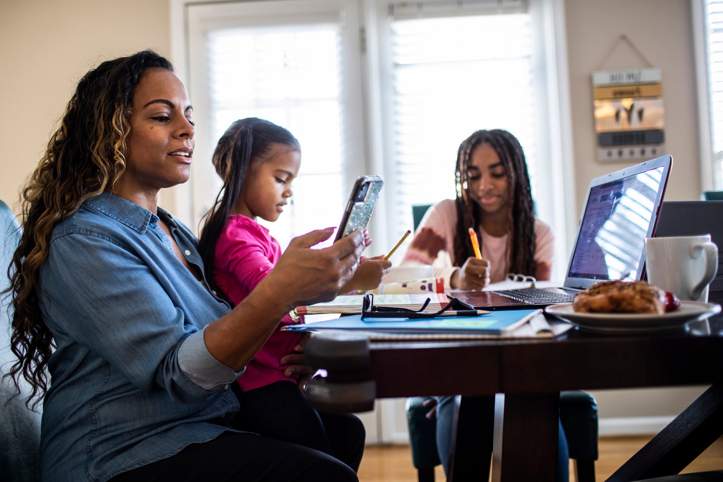family using internet on phone and laptop at home kitchen table