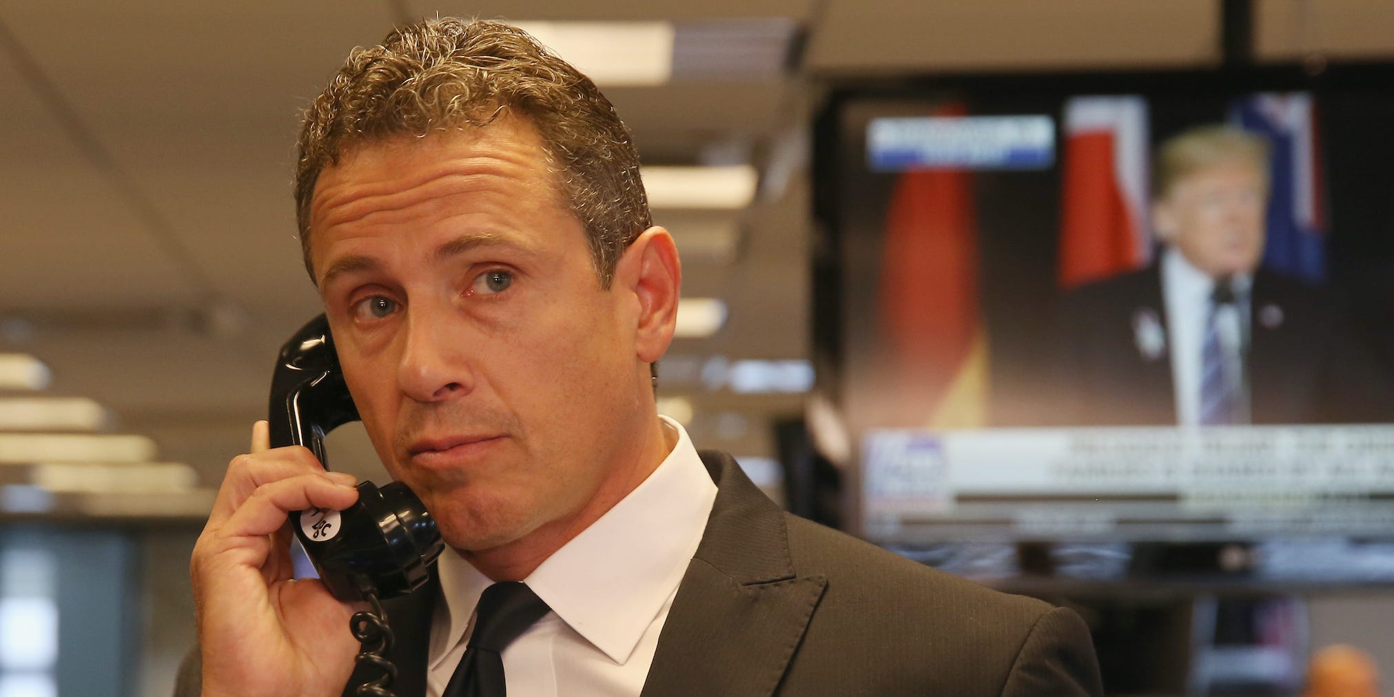 Chris Cuomo holds a landline phone to his ear, looking off to his left.