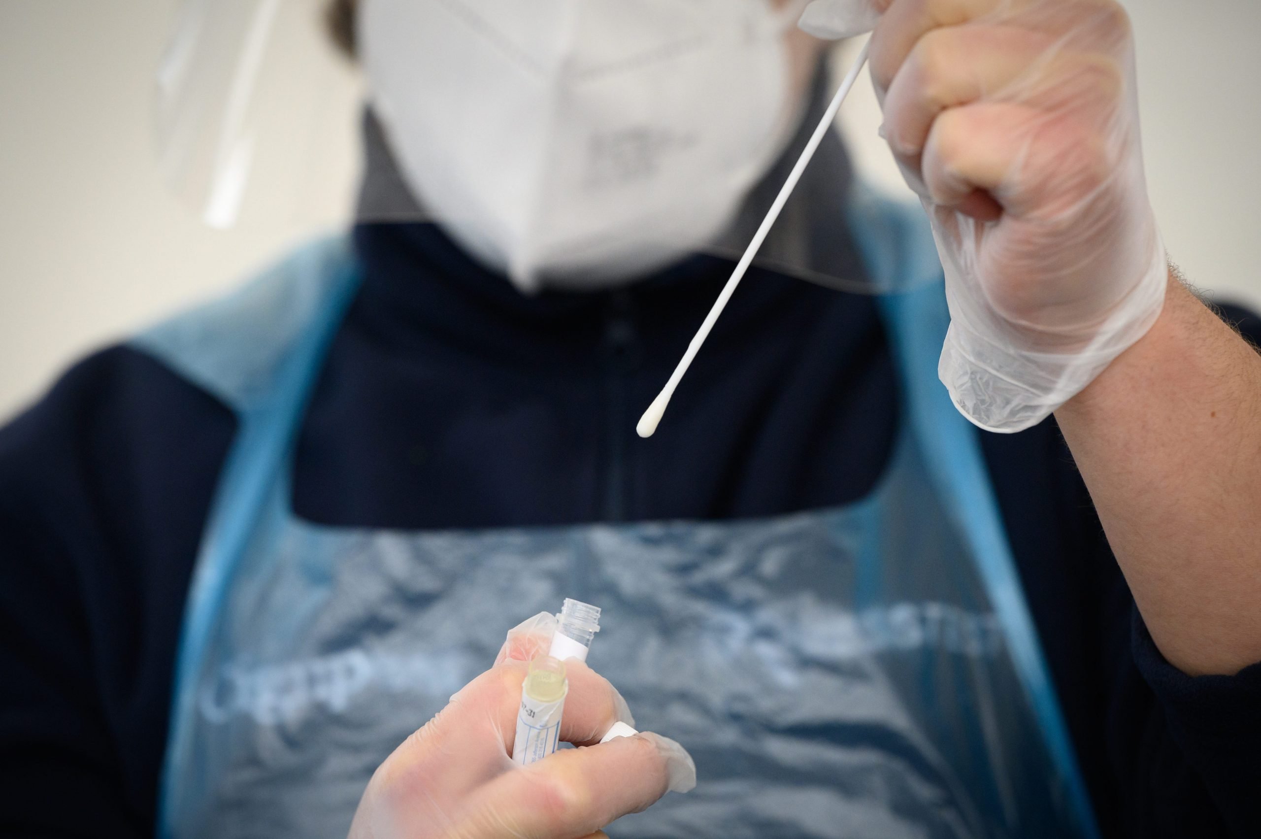 member of the medical team holds up a used swab from a PCR test at Gatwick Airport on November 27, 2020 in London, England.