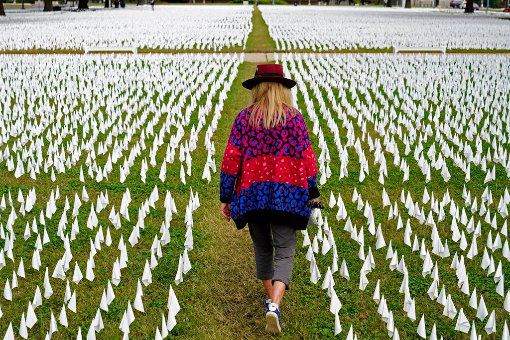 In this Oct. 27, 2020, file photo, Artist Suzanne Brennan Firstenberg walks among thousands of white flags planted in remembrance of Americans who have died of COVID-19 near Robert F. Kennedy Memorial Stadium in Washington.