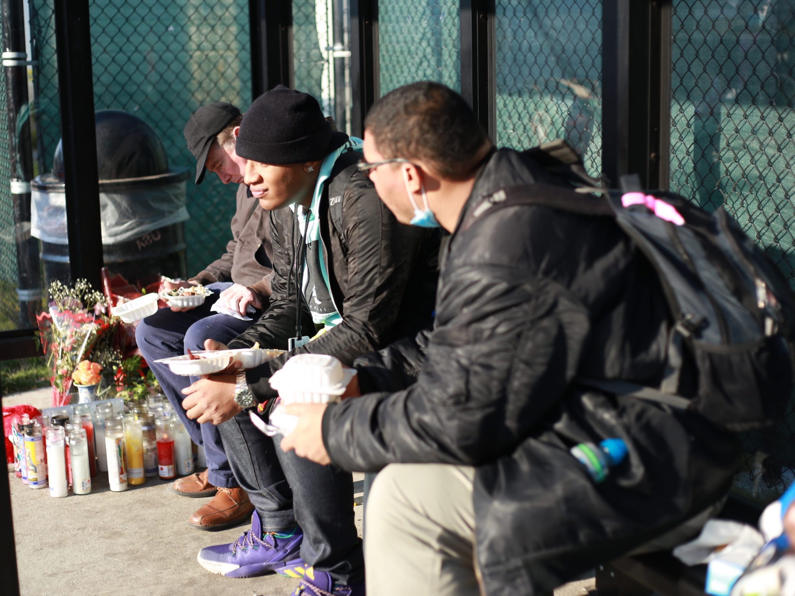 People sit at the bus stop and eat food made by the Amazon Labor Union outside the Staten Island JFK8 warehouse on Thanksgiving 2021.