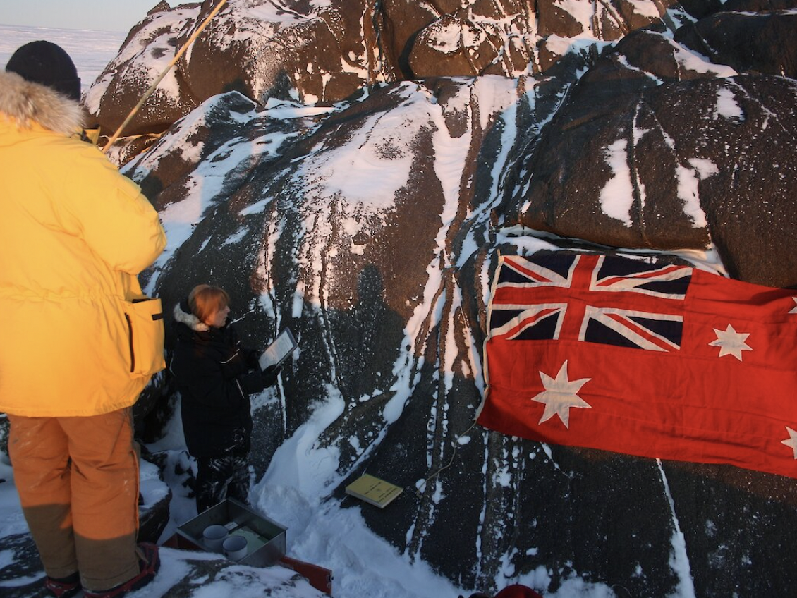 Expeditioners reading Sir Hubert Wilkins’ proclamation at Wilkins Cairn.