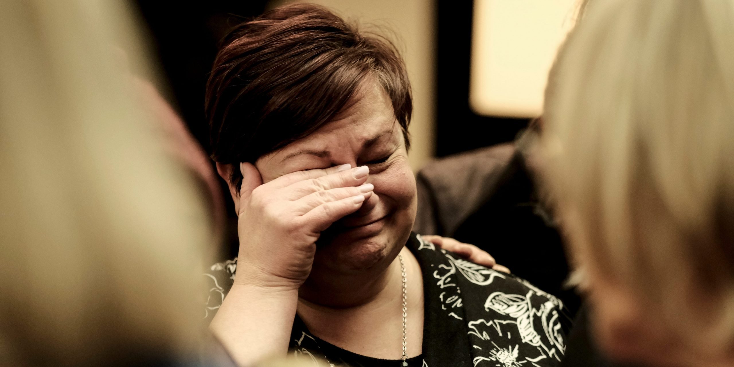 woman holding hand over eyes as she cries following oxford high school shooting