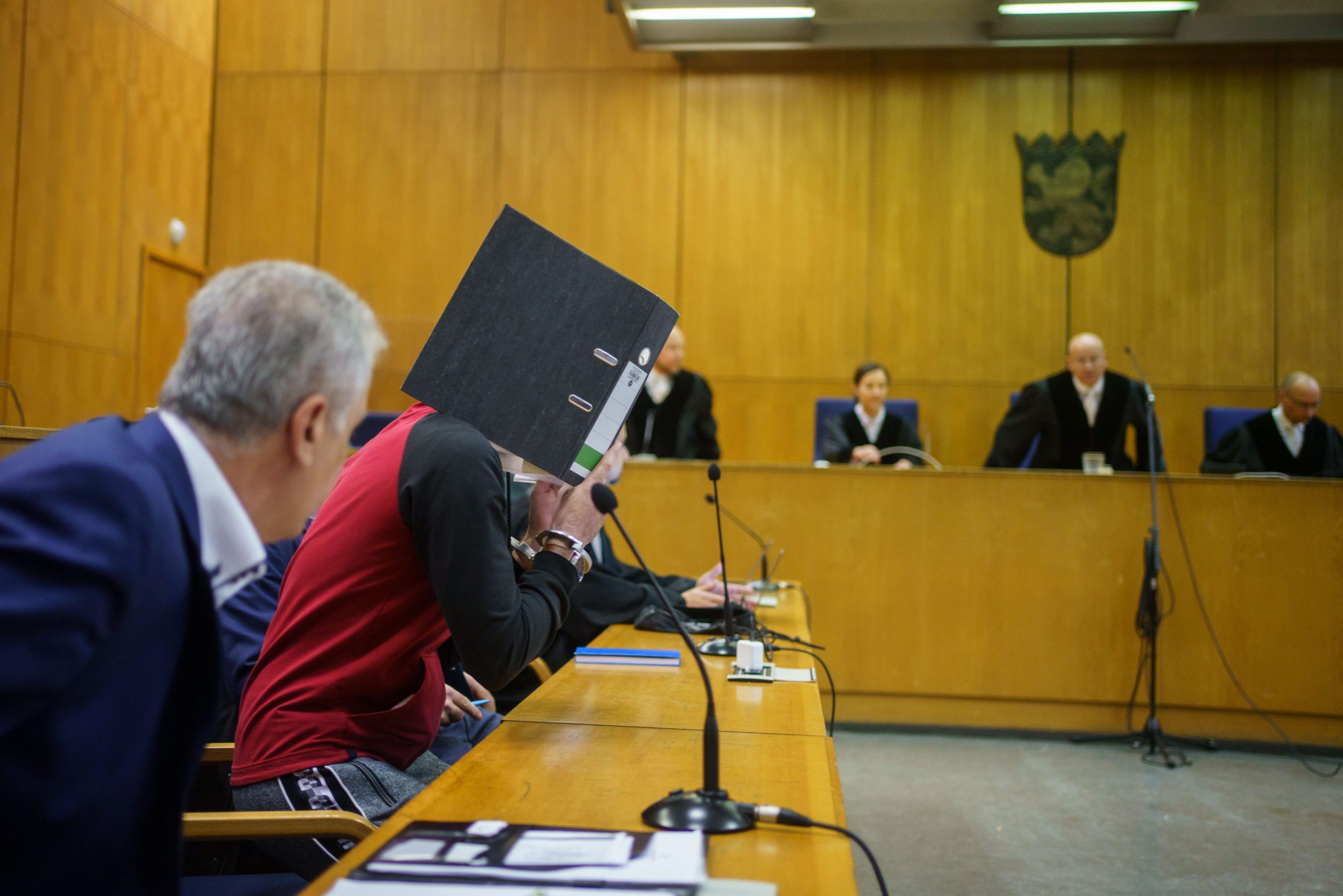 Iraqi Taha Al-J. hides his face behind a folder before the judgment is pronounced