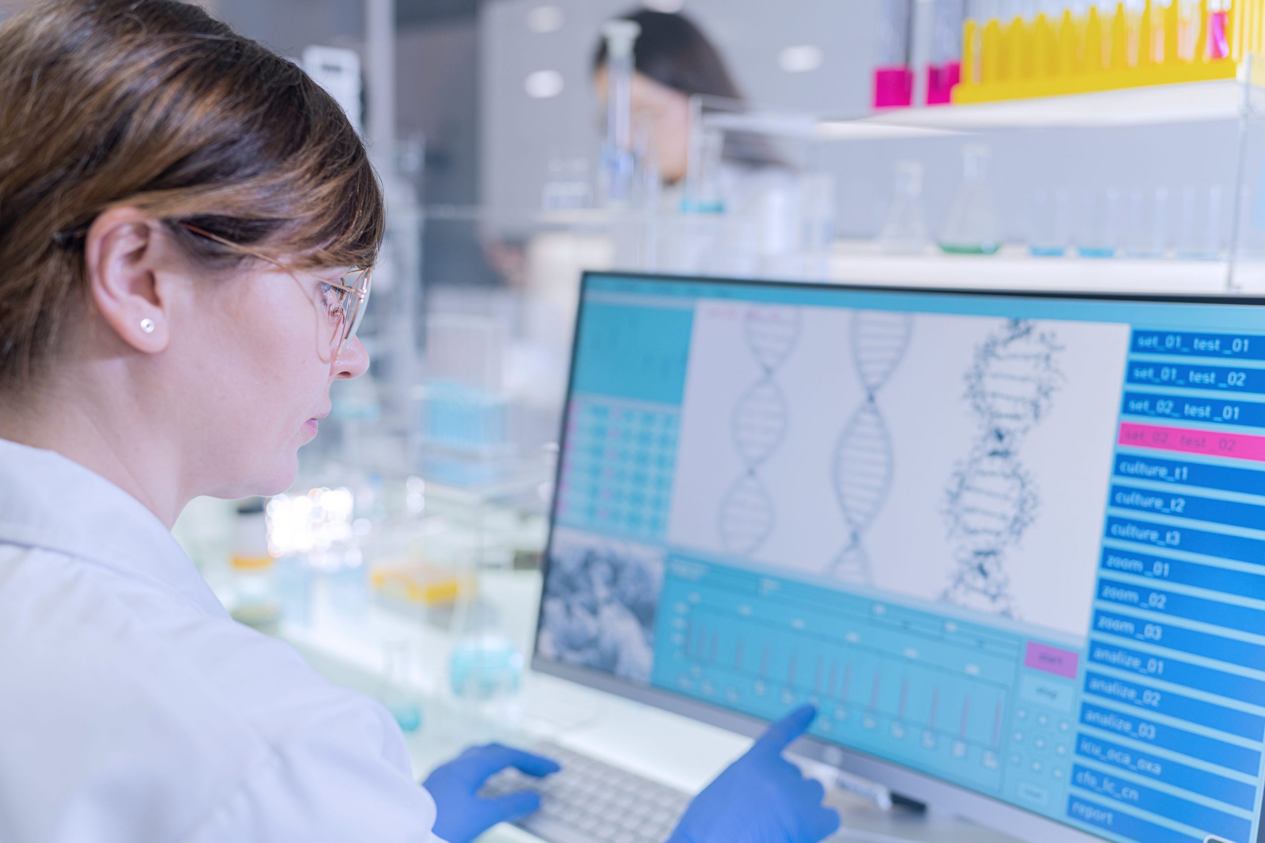 A female scientist examines computer images of DNA models.