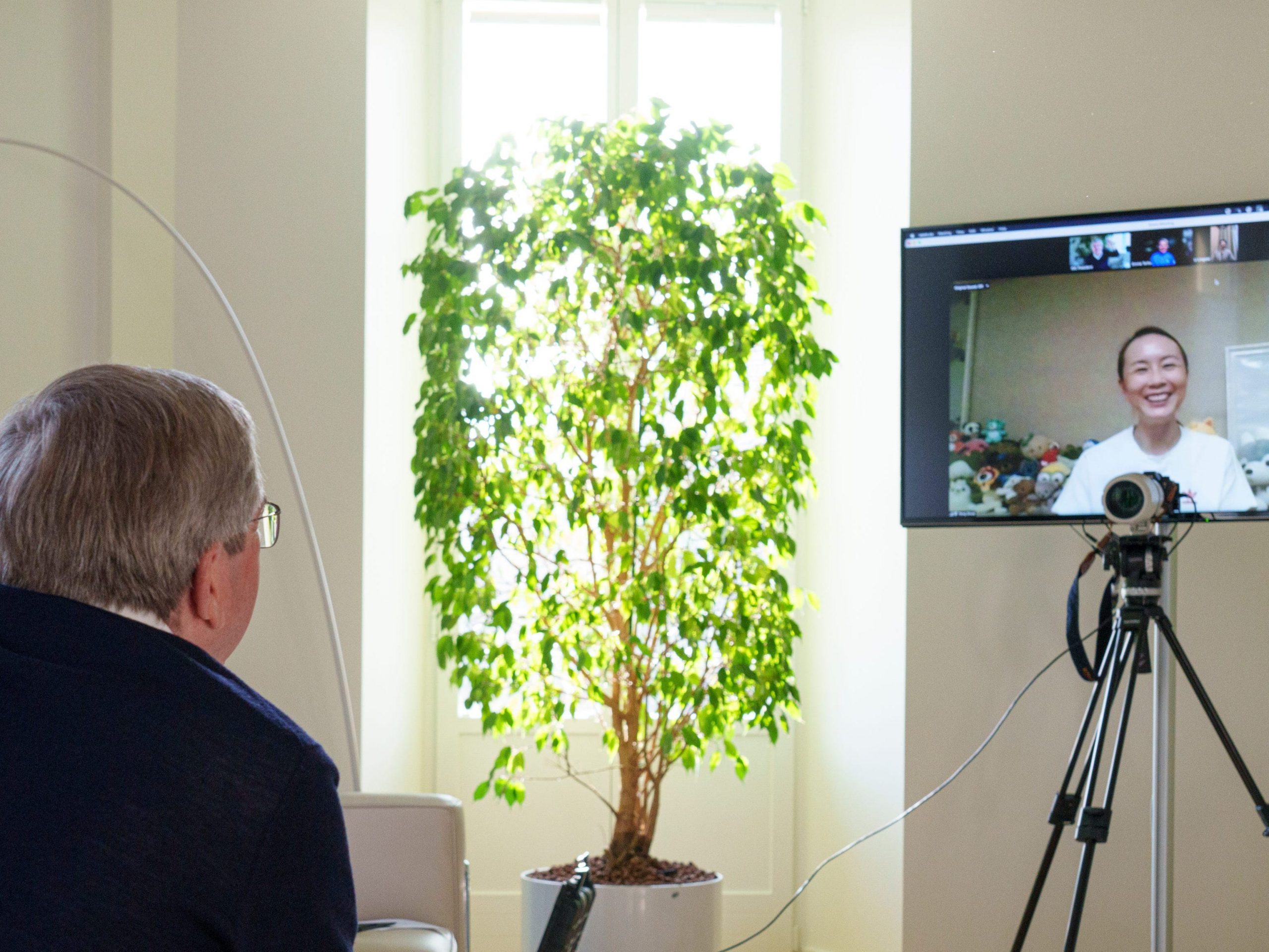 A man turned away from the camera, looking at a screen with a woman smiling.