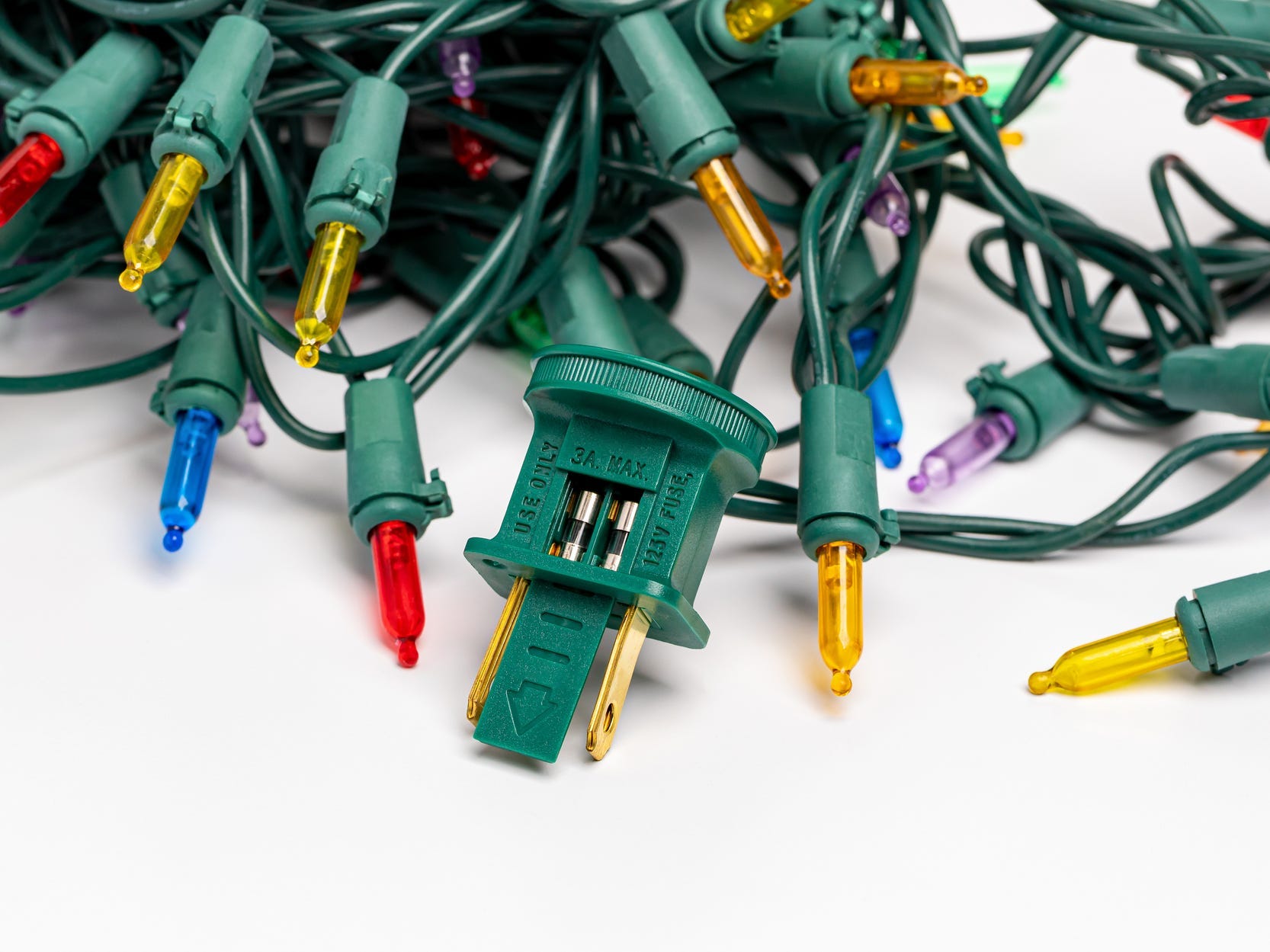 Colorful string lights in a pile with the plug open to expose the fuses