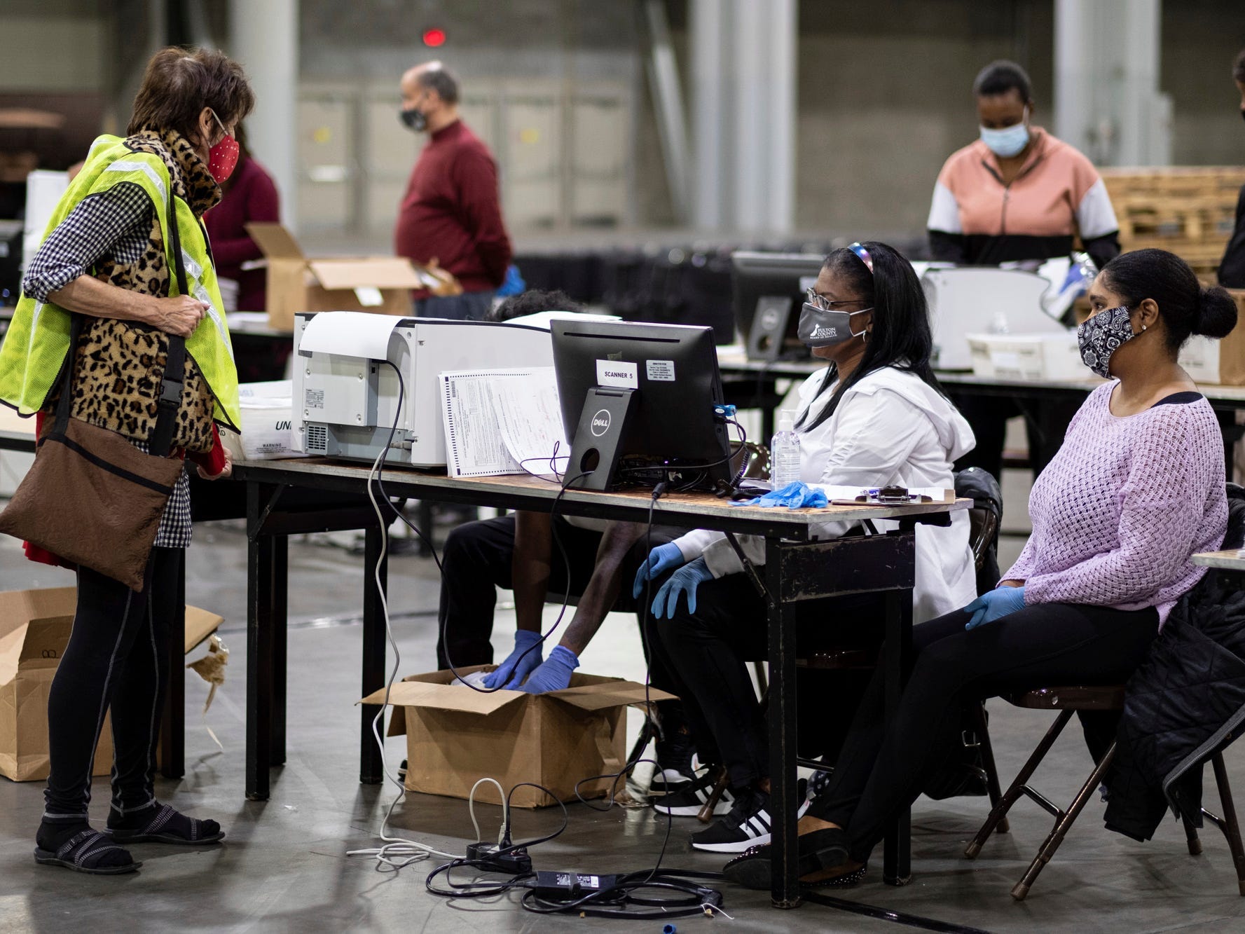 A GOP observer, left, watches as workers scan ballots as the Fulton County presidential recount gets under way Wednesday morning, Nov. 25, 2020 at the Georgia World Congress Center in Atlanta.